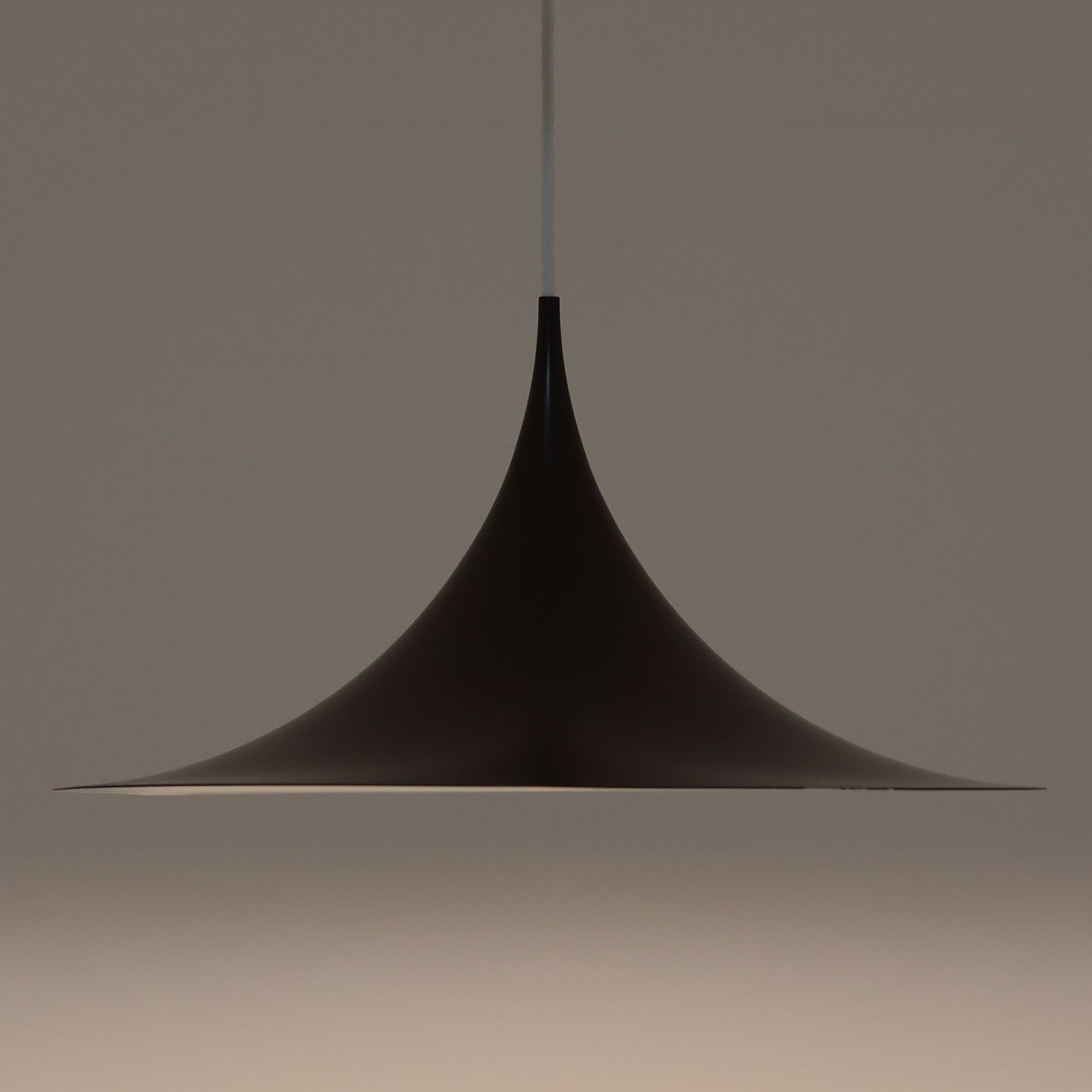 Claus BonderupとTorsten Thorupによるデザインのペンダントライト「Semi」は、Fog & Morup社から発表された北欧モダンを象徴する名作です。直径47cmのアルミシェードは美しい円錐を上下で切り取ったような独特のフォルムを持ち、光を下方向へ効率的に導きます。そのシャープでミニマルな造形は、空間にモダンな緊張感と優雅さをもたらし、ダイニングやリビングの中心を引き立てます。ビンテージならではの希少性と時を経た質感が一層の魅力を添え、北欧デザインの洗練を感じさせる一灯です。