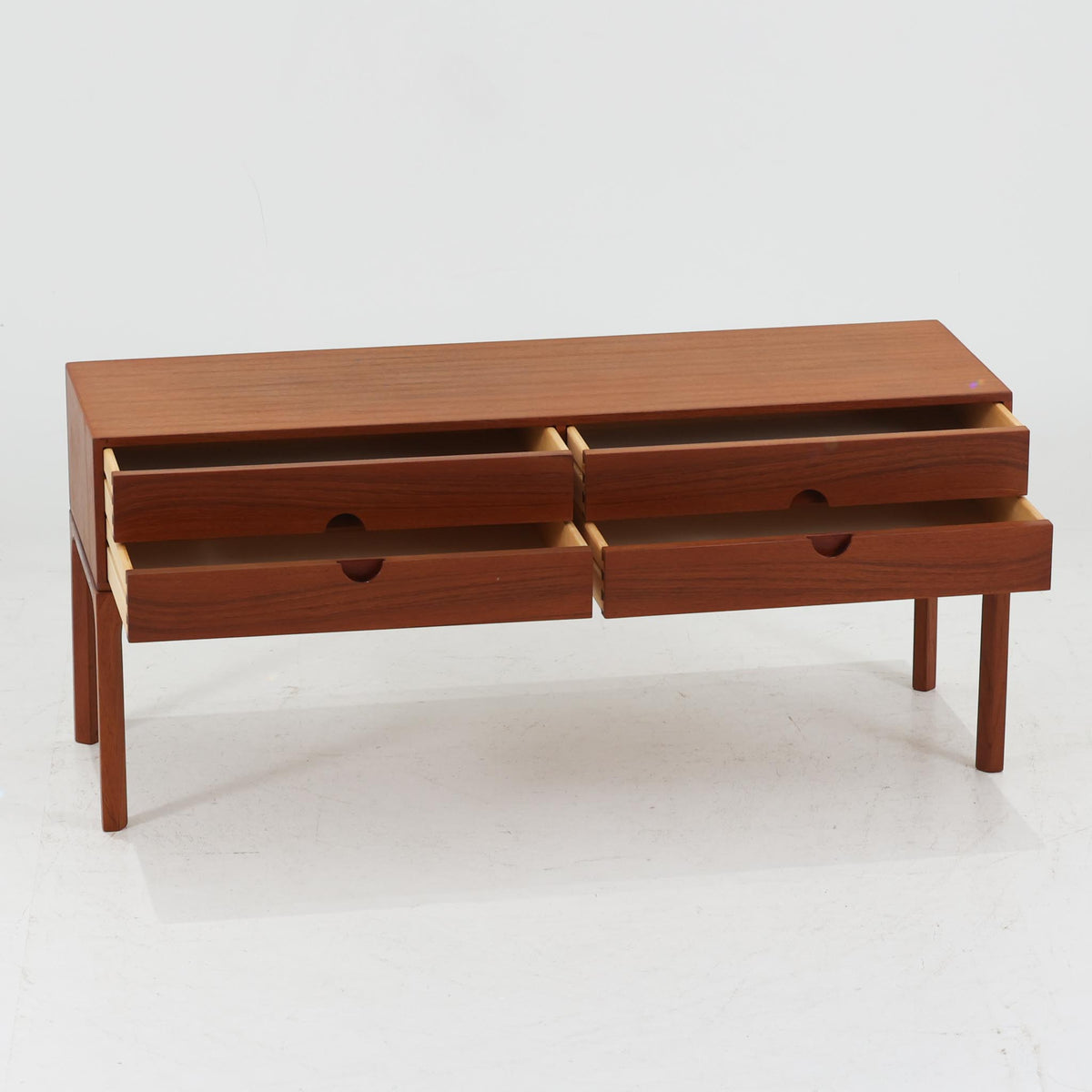 デンマークのデザイナー、Kai Kristiansen（カイ・クリスチャンセン）が手がけ、Aksel Kjersgaard（アクセル・キアスゴー）によって製造されたModel 394。チーク材の美しい木目と温かみのある色合いが魅力で、直線的なフォルムとすっきりとした脚部が、北欧ミッドセンチュリーらしい洗練された佇まいを演出します。左右に配置された計4杯の引き出しには、上下の引き出しにまたがる円形のくぼみが設けられ、装飾性と機能性を兼ね備えた特徴的なデザインに仕上げられています。年月を重ねた木肌の豊かな風合いも魅力のひとつ。リビングでの小物収納やテレビボードとしてはもちろん、玄関や寝室などでも活躍する、実用性と造形美を兼ね備えた一品です。