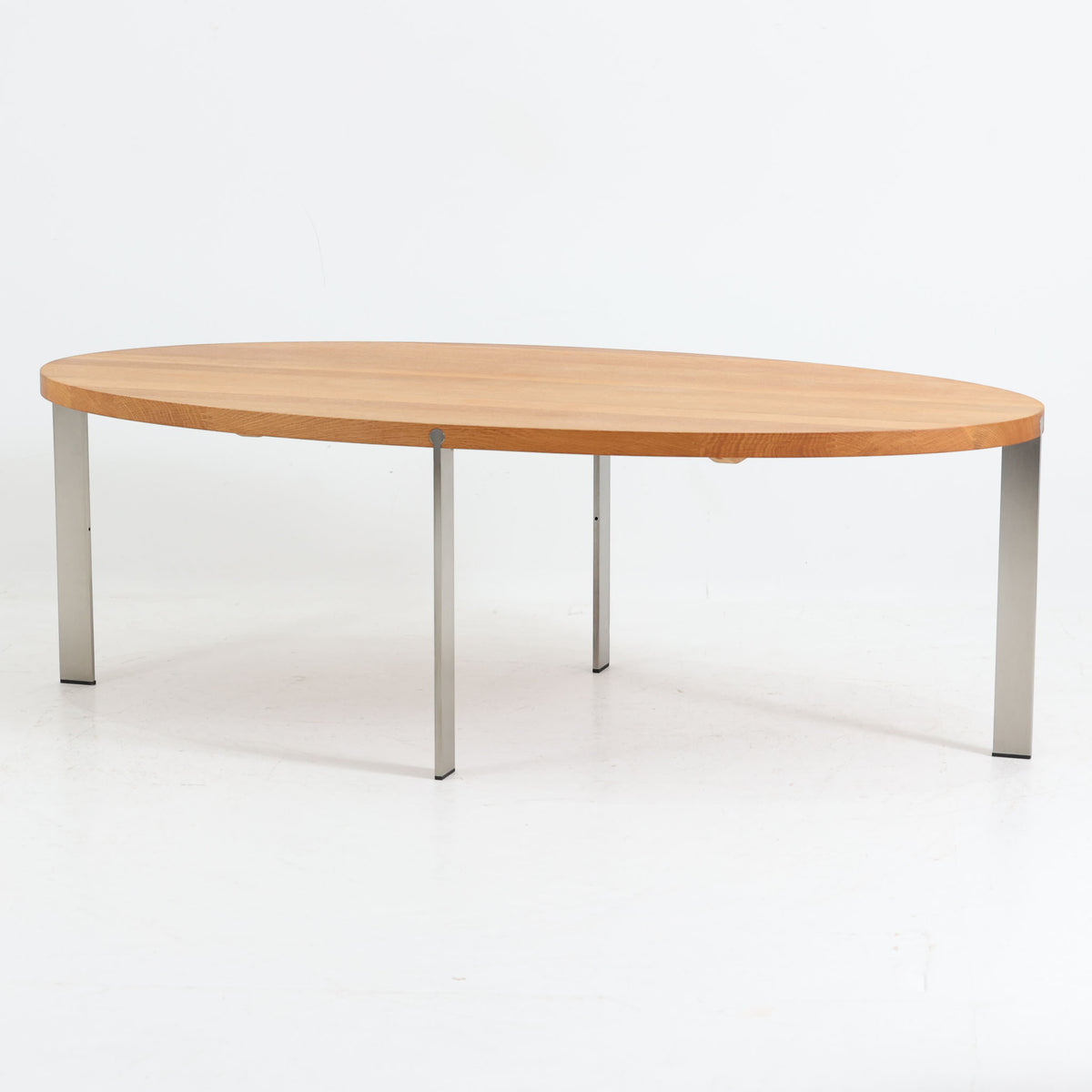 Nissen &amp; Gehlがデザインし、Aksel Kjersgaardが製造したオーク無垢材のセンターテーブルです。楕円形の天板に細身の金属脚を組み合わせた、木と金属のコントラストが印象的な構成で、幅137cmながら軽やかな佇まいに仕上げられています。無垢材ならではの豊かな木目と厚みのある天板、シャープな脚部の対比に洗練された職人技が感じられ、経年による穏やかな風合いとともに、リビングの中心で上品な存在感を放つ一台です。
