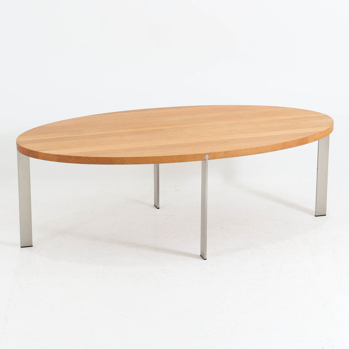 Nissen &amp; Gehlがデザインし、Aksel Kjersgaardが製造したオーク無垢材のセンターテーブルです。楕円形の天板に細身の金属脚を組み合わせた、木と金属のコントラストが印象的な構成で、幅137cmながら軽やかな佇まいに仕上げられています。無垢材ならではの豊かな木目と厚みのある天板、シャープな脚部の対比に洗練された職人技が感じられ、経年による穏やかな風合いとともに、リビングの中心で上品な存在感を放つ一台です。