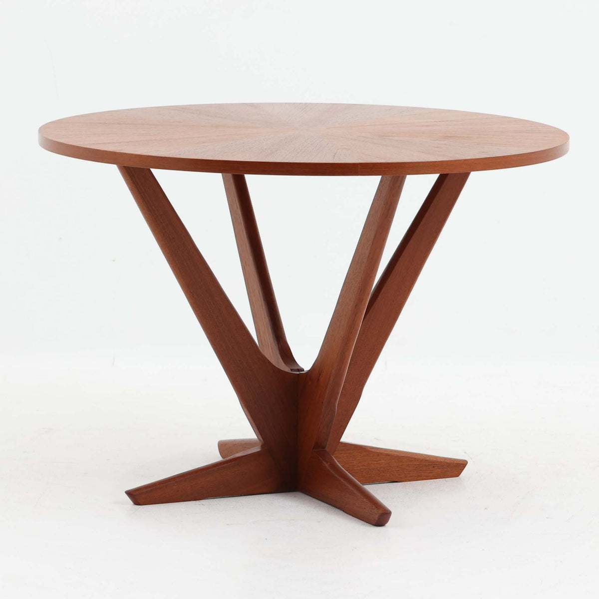 Holger Georg Jensen（ホルガー・ジョージ・イェンセン）がデザインし、Tonder Mobelvaerkが製造を手掛けた「Kubus」シリーズのセンターテーブルです。チーク材を用いた円形天板には中心から放射状に広がる美しい木目が表れ、中央へ向かって伸びる彫刻的な脚部と十字型のベースが印象的。直径78cmの程よいサイズで、ソファまわりにも取り入れやすく、経年を重ねたチークの深みある風合いと造形美を存分に楽しめる北欧ビンテージです。