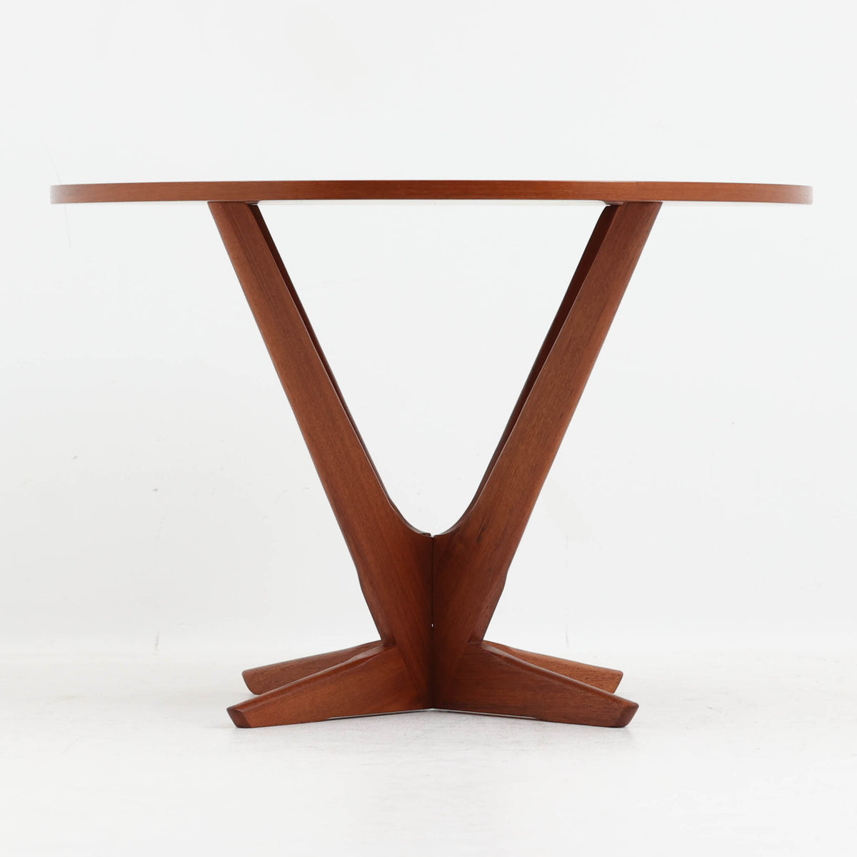 Holger Georg Jensen（ホルガー・ジョージ・イェンセン）がデザインし、Tonder Mobelvaerkが製造を手掛けた「Kubus」シリーズのセンターテーブルです。チーク材を用いた円形天板には中心から放射状に広がる美しい木目が表れ、中央へ向かって伸びる彫刻的な脚部と十字型のベースが印象的。直径78cmの程よいサイズで、ソファまわりにも取り入れやすく、経年を重ねたチークの深みある風合いと造形美を存分に楽しめる北欧ビンテージです。