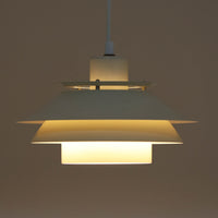 Dana Lightのデンマーク製ビンテージペンダントライトです。スチール製の複数のシェードを重ねた立体的な構造が特徴で、光源を直接見せにくくしながら、シェードの隙間や下方へ柔らかな光を広げます。アイボリー系の落ち着いた色合いと端正なフォルムは空間に馴染みやすく、ダイニングやキッチン、玄関など幅広い場所におすすめ。点灯時には各シェードに光の濃淡が生まれ、北欧ビンテージ照明ならではの温かみある佇まいを楽しめます。