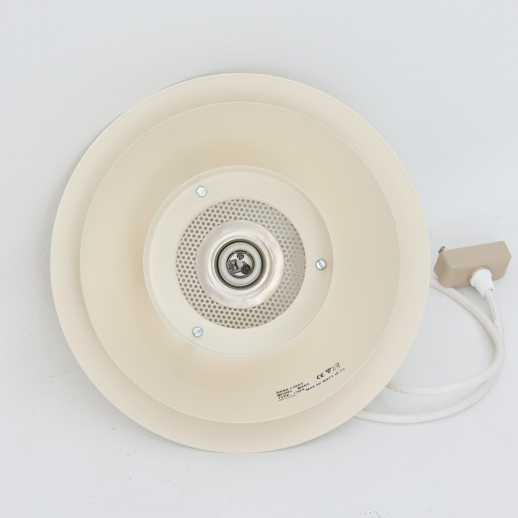Dana Lightのデンマーク製ビンテージペンダントライトです。スチール製の複数のシェードを重ねた立体的な構造が特徴で、光源を直接見せにくくしながら、シェードの隙間や下方へ柔らかな光を広げます。アイボリー系の落ち着いた色合いと端正なフォルムは空間に馴染みやすく、ダイニングやキッチン、玄関など幅広い場所におすすめ。点灯時には各シェードに光の濃淡が生まれ、北欧ビンテージ照明ならではの温かみある佇まいを楽しめます。