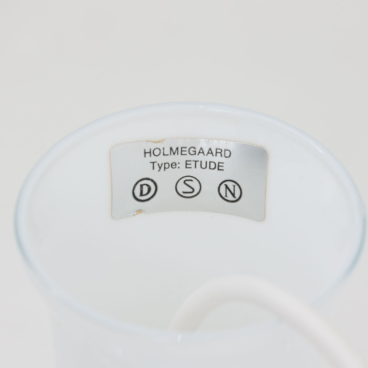 Holmegaardの「Etude」は、Michael Bang（マイケル・バング）が手掛けたガラス製のペンダントライトです。乳白色のガラスを用い、細く伸びるネックからふくらみを持たせた中央部、裾へ向かって大きく広がるシェードへと続く流麗なフォルムが印象的。存在感がありながら、ガラスならではの柔らかな光と軽やかな佇まいを楽しめます。ダイニングテーブルやリビングの主照明としても取り入れやすく、造形そのものの美しさも楽しめる北欧ビンテージ照明です。