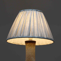 デンマークの陶磁器メーカーAxella Keramik（アクセラ）による、Jette Helleroe（イェッテ・ヘレロー）デザインのビンテージテーブルランプ。すらりと伸びた細身の首元と、ふっくらと丸みを帯びたベースが印象的な、美しいシルエットの一台です。陶磁器製の本体には、アイボリーを基調とした柔らかな色合いに、深みのあるブラウンの釉薬が大胆に施され、流れるような色の境界や自然な濃淡が豊かな表情を生み出しています。釉薬の重なりによって生まれる独特の風合いには、手仕事ならではの温もりと芸術性が感じられます。プリーツを施したリネンシェードは柔らかな光を広げ、存在感のあるベースとの美しい調和を演出します。リビングのサイドボードや寝室など、空間を印象的に彩るアクセント照明としておすすめです。