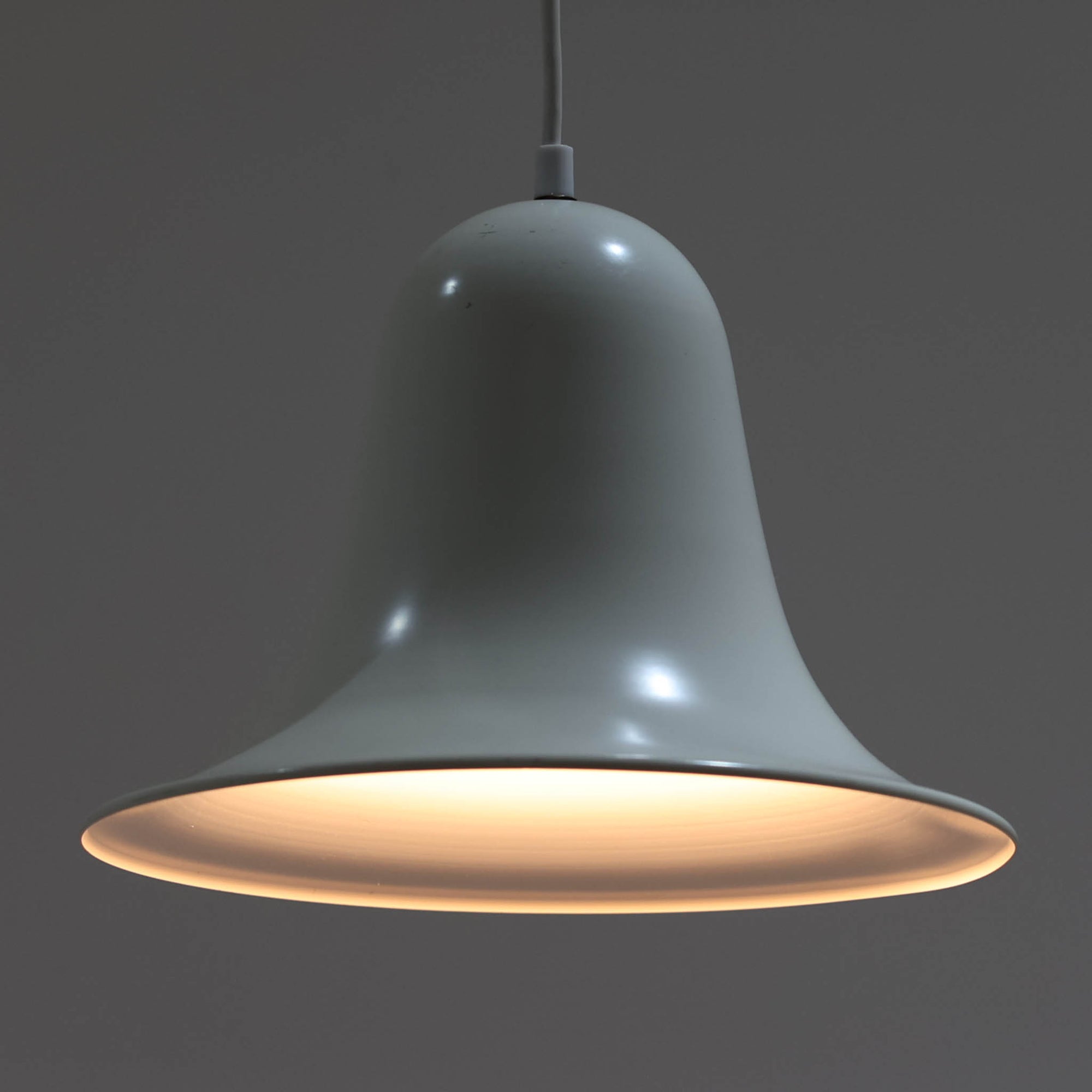 Verner Panton（ヴェルナー・パントン）による「Pantop」のペンダントライトです。アルミ製のシェードは、ベルを思わせる滑らかな曲線と大きく広がる裾が特徴で、シンプルながら彫刻的な存在感を備えています。光源をシェード内に収める構造により、点灯時には下方へ柔らかな光が広がり、ダイニングテーブルやカウンター上の照明としてもおすすめ。直径30cmの取り入れやすいサイズで、時代を経ても色褪せない造形美を楽しめる北欧ビンテージならではの一灯です。