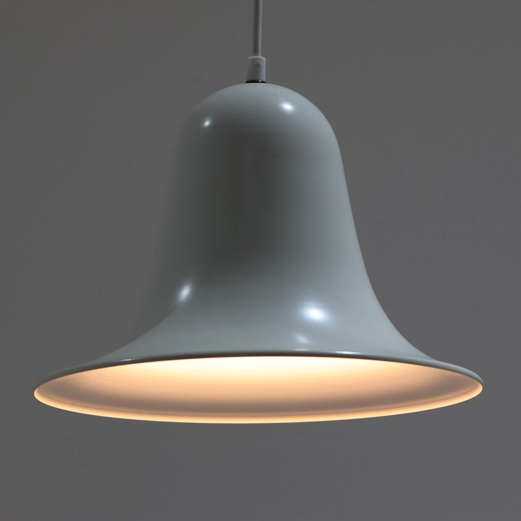 Verner Panton（ヴェルナー・パントン）による「Pantop」のペンダントライトです。アルミ製のシェードは、ベルを思わせる滑らかな曲線と大きく広がる裾が特徴で、シンプルながら彫刻的な存在感を備えています。光源をシェード内に収める構造により、点灯時には下方へ柔らかな光が広がり、ダイニングテーブルやカウンター上の照明としてもおすすめ。直径30cmの取り入れやすいサイズで、時代を経ても色褪せない造形美を楽しめる北欧ビンテージならではの一灯です。