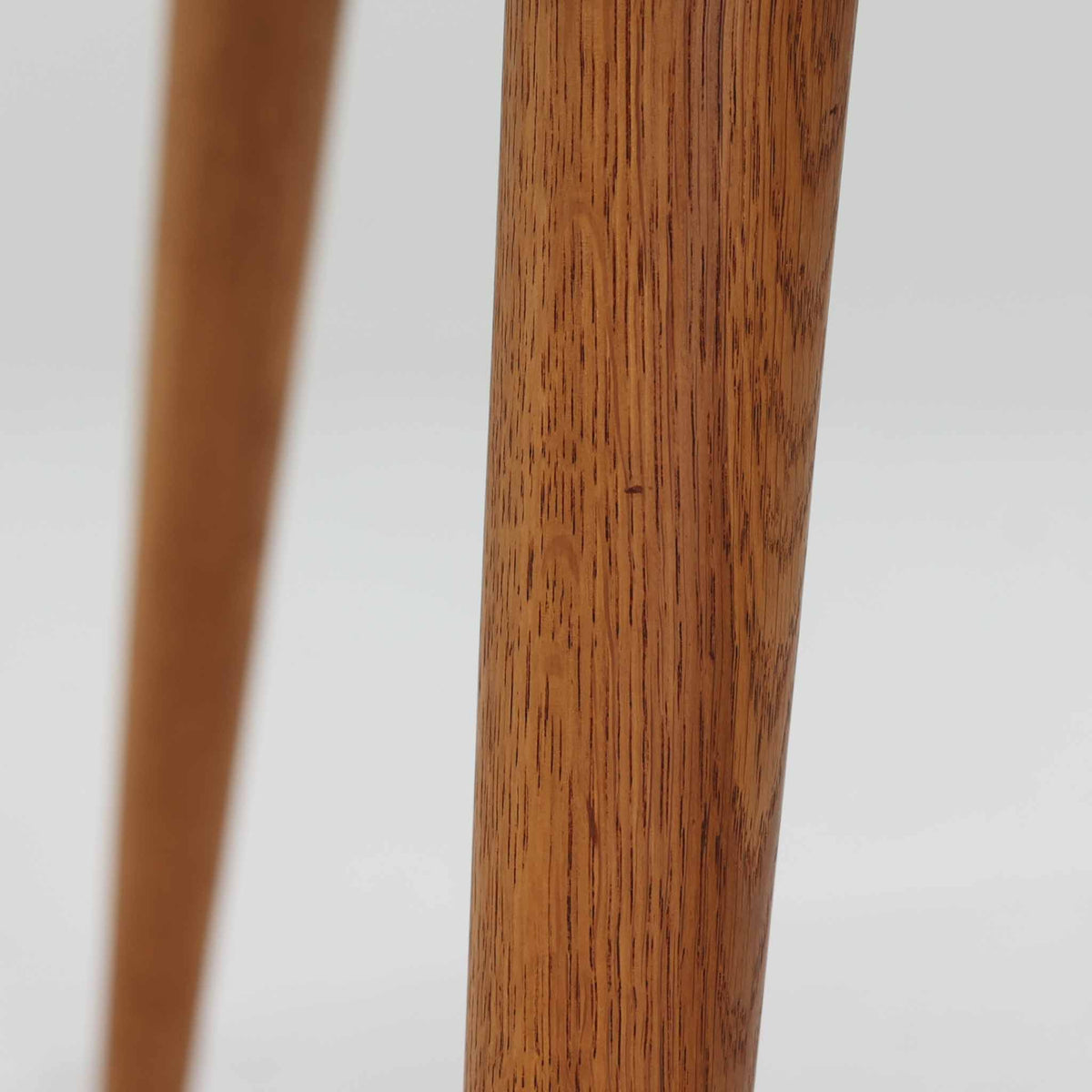 Hans J. Wegnerがデザインし、Andreas Tuckが製造を手掛けたAT8。チーク材の円形天板とオーク材の脚部を組み合わせ、異なる木材の表情を巧みに生かした一台です。直径98cmの伸びやかな天板を、外側へ緩やかに開く4本のテーパードレッグが軽快に支えるシンプルな構成で、素材とプロポーションの美しさが際立ちます。ソファを囲むリビングの主役として取り入れやすく、ウェグナーらしい端正な造形と年月を重ねた木部の風合いを味わえるビンテージ品です。