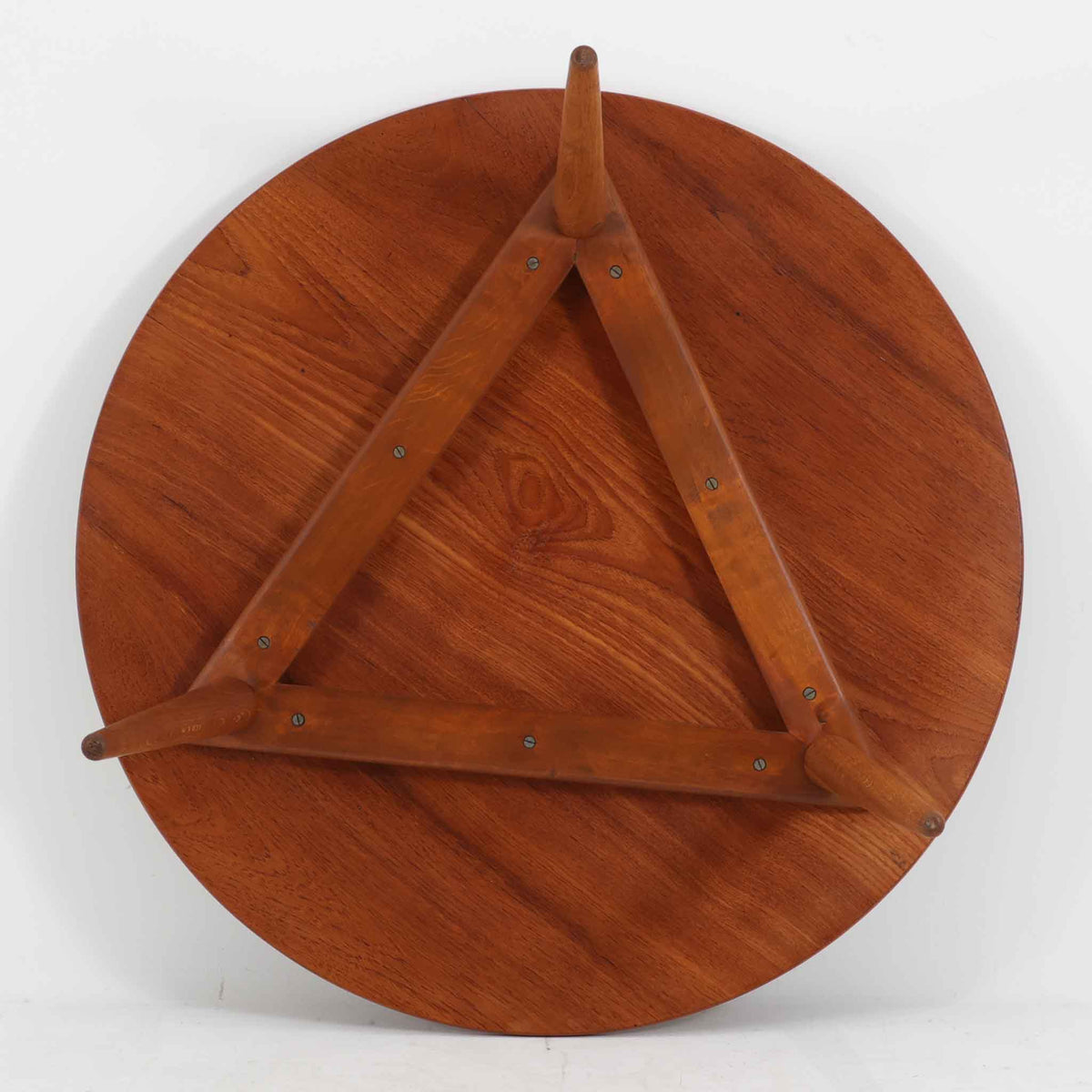 Hans J. Wegnerがデザインし、Andreas Tuckが製造を手掛けたAT8。チーク材の円形天板とオーク材の脚部を組み合わせ、異なる木材の表情を巧みに生かした一台です。直径98cmの伸びやかな天板を、外側へ緩やかに開く4本のテーパードレッグが軽快に支えるシンプルな構成で、素材とプロポーションの美しさが際立ちます。ソファを囲むリビングの主役として取り入れやすく、ウェグナーらしい端正な造形と年月を重ねた木部の風合いを味わえるビンテージ品です。