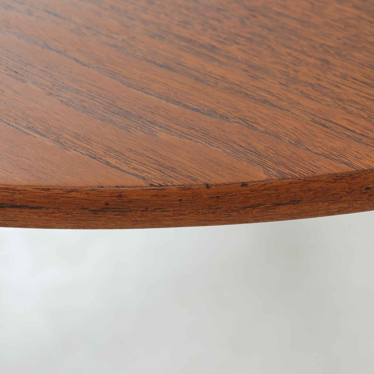 Hans J. Wegnerがデザインし、Andreas Tuckが製造を手掛けたAT8。チーク材の円形天板とオーク材の脚部を組み合わせ、異なる木材の表情を巧みに生かした一台です。直径98cmの伸びやかな天板を、外側へ緩やかに開く4本のテーパードレッグが軽快に支えるシンプルな構成で、素材とプロポーションの美しさが際立ちます。ソファを囲むリビングの主役として取り入れやすく、ウェグナーらしい端正な造形と年月を重ねた木部の風合いを味わえるビンテージ品です。