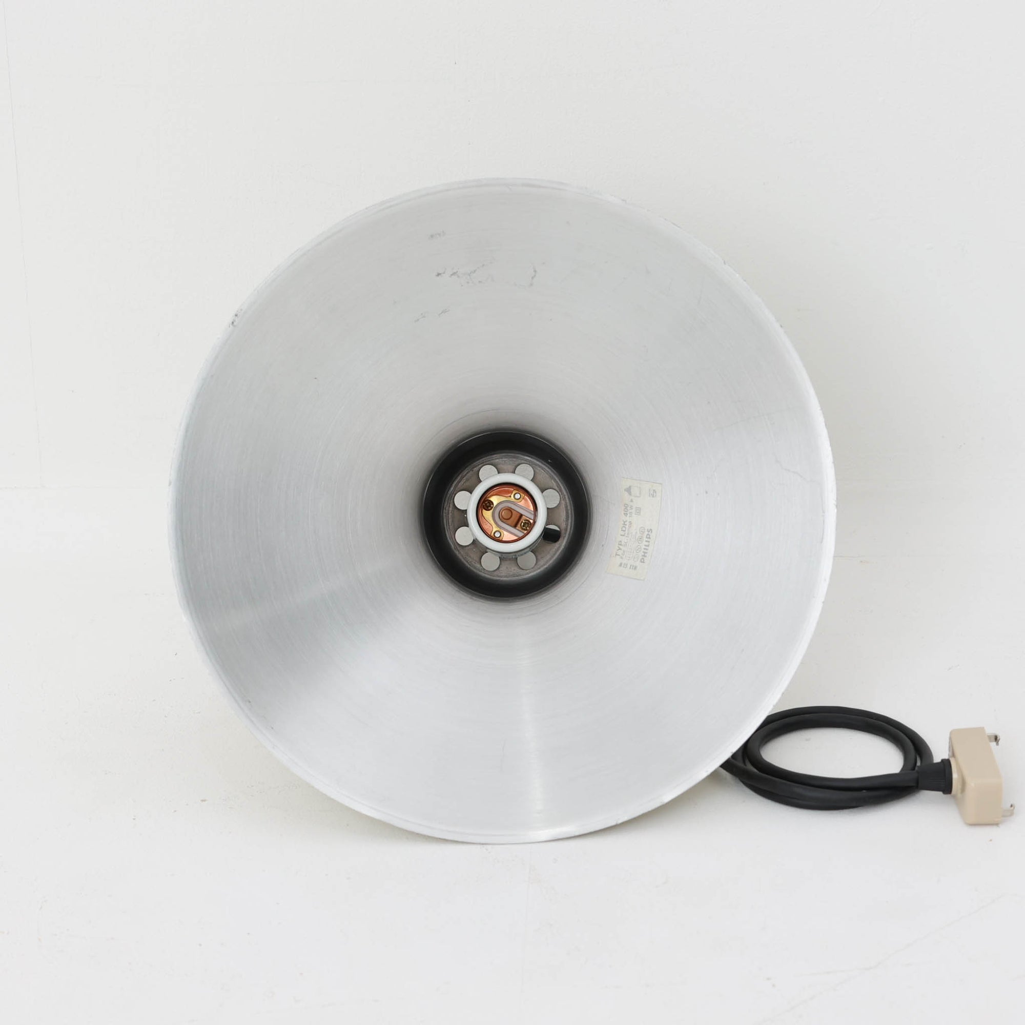 Philipsのモデル「LDK 400」、デンマーク製のビンテージペンダントライトです。アルミを用いたシンプルな一枚シェードは、上部から裾に向かって緩やかに広がる美しいフォルムが特徴。直径29cmと程よいサイズで、ダイニングやキッチン、カウンターなどにも取り入れやすく、金属の落ち着いた質感が空間を上品に演出します。無駄を抑えた端正な造形と経年による風合いに、北欧ビンテージ照明らしい趣が感じられる一灯です。