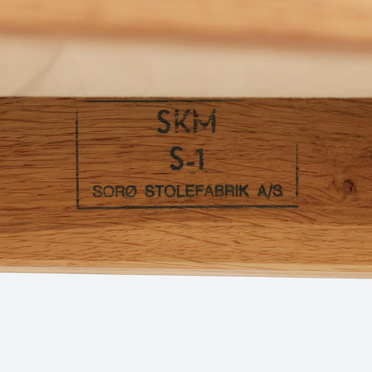 Soro Stolefabrik（ソロ・ストールファブリック）が手掛けた、チーク材とオーク材を組み合わせた北欧ビンテージのアームチェア。明るく美しい木目のオーク材を主体としたフレームに、深みのある色合いのチーク材をアームレストに使用し、異なる木材のコントラストが上品なアクセントを添えています。緩やかな曲線を描く背もたれには幾何学模様のファブリックを合わせ、柔らかな色合いの座面とともに落ち着いた雰囲気を演出。直線的な脚部や貫を組み合わせた構造には、北欧家具らしい機能美と丁寧な木工技術が感じられます。ダイニングや書斎の椅子としてはもちろん、リビングの一角に置くアクセントチェアとしてもおすすめの、温もりとビンテージならではの味わいを兼ね備えた一脚です。