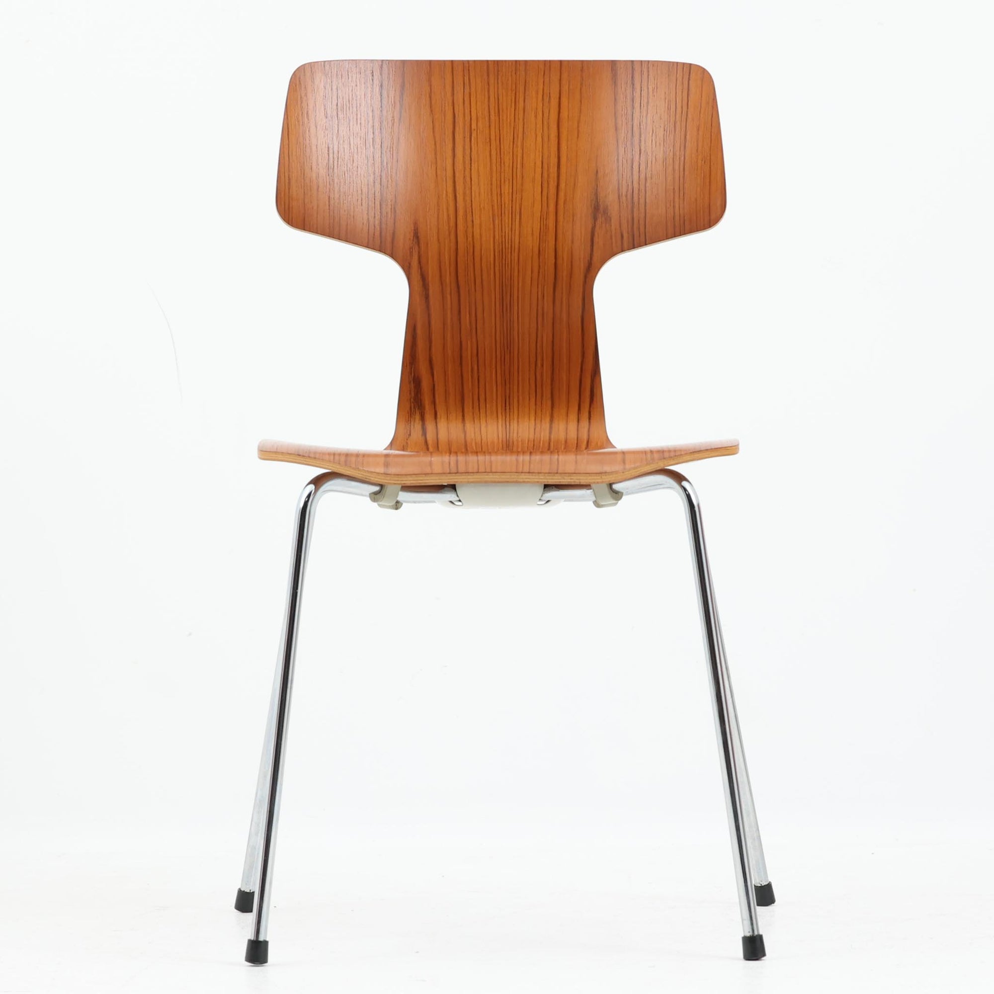 アルネ・ヤコブセンがデザインし、Fritz Hansenが製造した「T Chair」です。チーク材の成形合板による背座一体型のシェルは、背面上部を左右に広げた特徴的なシルエットと、身体に沿う緩やかな曲面が魅力。細身の金属脚との組み合わせが軽快で、ダイニングはもちろん、書斎や玄関のアクセントチェアにもおすすめです。美しい木目と時を重ねた風合い、合理的な構造に宿る北欧ビンテージらしい存在感を楽しめます。