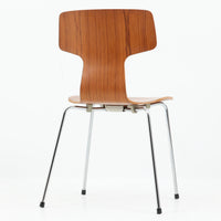 アルネ・ヤコブセンがデザインし、Fritz Hansenが製造した「T Chair」です。チーク材の成形合板による背座一体型のシェルは、背面上部を左右に広げた特徴的なシルエットと、身体に沿う緩やかな曲面が魅力。細身の金属脚との組み合わせが軽快で、ダイニングはもちろん、書斎や玄関のアクセントチェアにもおすすめです。美しい木目と時を重ねた風合い、合理的な構造に宿る北欧ビンテージらしい存在感を楽しめます。