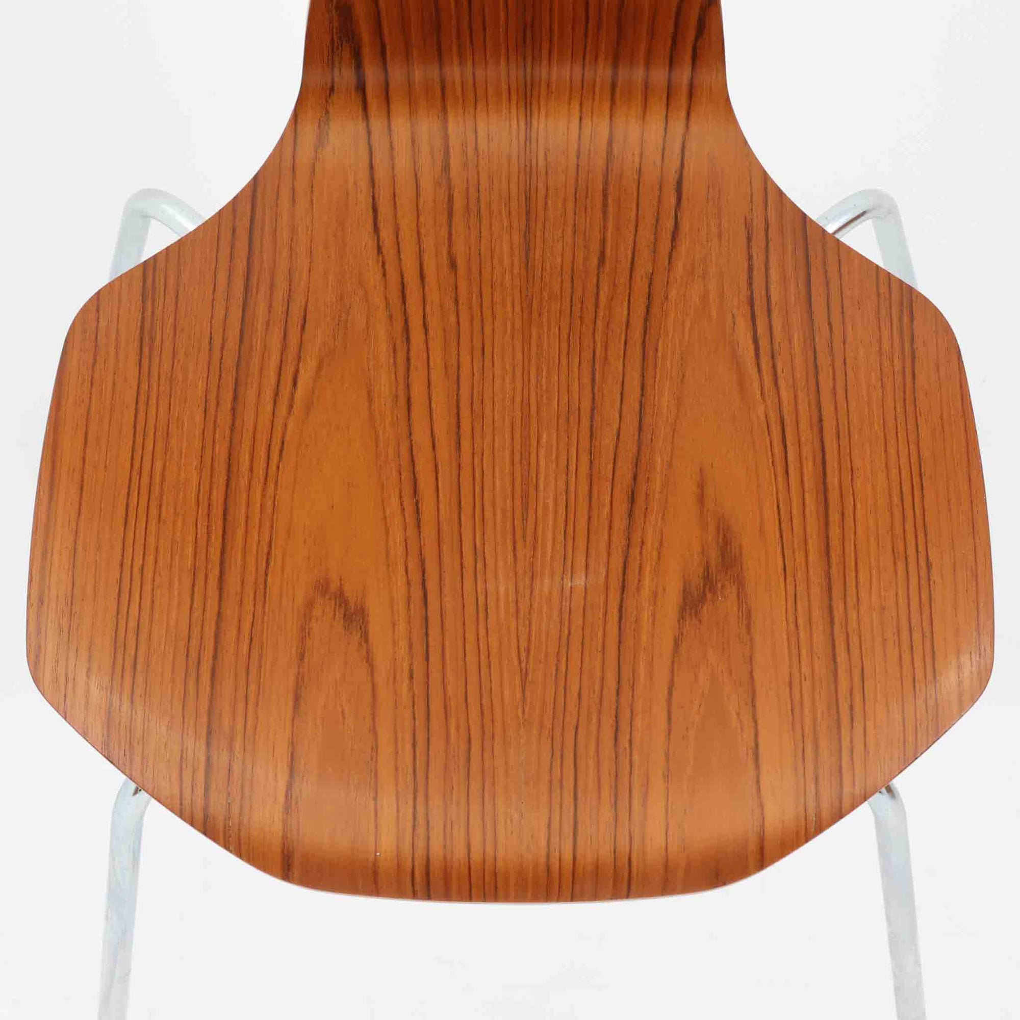 アルネ・ヤコブセンがデザインし、Fritz Hansenが製造した「T Chair」です。チーク材の成形合板による背座一体型のシェルは、背面上部を左右に広げた特徴的なシルエットと、身体に沿う緩やかな曲面が魅力。細身の金属脚との組み合わせが軽快で、ダイニングはもちろん、書斎や玄関のアクセントチェアにもおすすめです。美しい木目と時を重ねた風合い、合理的な構造に宿る北欧ビンテージらしい存在感を楽しめます。