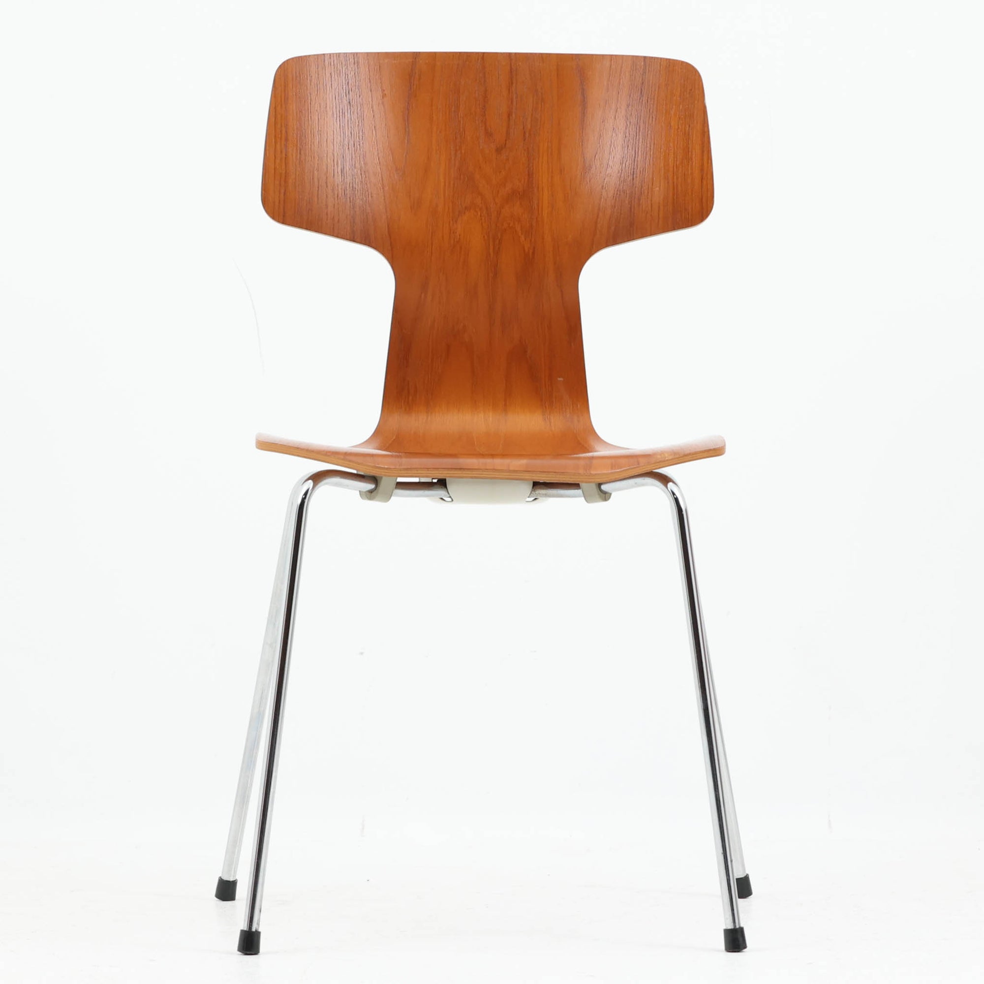 アルネ・ヤコブセンがデザインし、Fritz Hansenが製造した「T Chair」です。チーク材の成形合板による背座一体型のシェルは、背面上部を左右に広げた特徴的なシルエットと、身体に沿う緩やかな曲面が魅力。細身の金属脚との組み合わせが軽快で、ダイニングはもちろん、書斎や玄関のアクセントチェアにもおすすめです。美しい木目と時を重ねた風合い、合理的な構造に宿る北欧ビンテージらしい存在感を楽しめます。