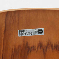 アルネ・ヤコブセンがデザインし、Fritz Hansenが製造した「T Chair」です。チーク材の成形合板による背座一体型のシェルは、背面上部を左右に広げた特徴的なシルエットと、身体に沿う緩やかな曲面が魅力。細身の金属脚との組み合わせが軽快で、ダイニングはもちろん、書斎や玄関のアクセントチェアにもおすすめです。美しい木目と時を重ねた風合い、合理的な構造に宿る北欧ビンテージらしい存在感を楽しめます。