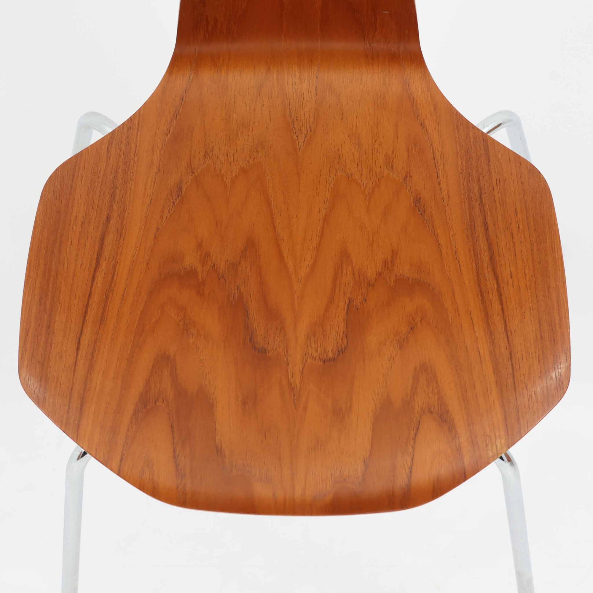 アルネ・ヤコブセンがデザインし、Fritz Hansenが製造した「T Chair」です。チーク材の成形合板による背座一体型のシェルは、背面上部を左右に広げた特徴的なシルエットと、身体に沿う緩やかな曲面が魅力。細身の金属脚との組み合わせが軽快で、ダイニングはもちろん、書斎や玄関のアクセントチェアにもおすすめです。美しい木目と時を重ねた風合い、合理的な構造に宿る北欧ビンテージらしい存在感を楽しめます。