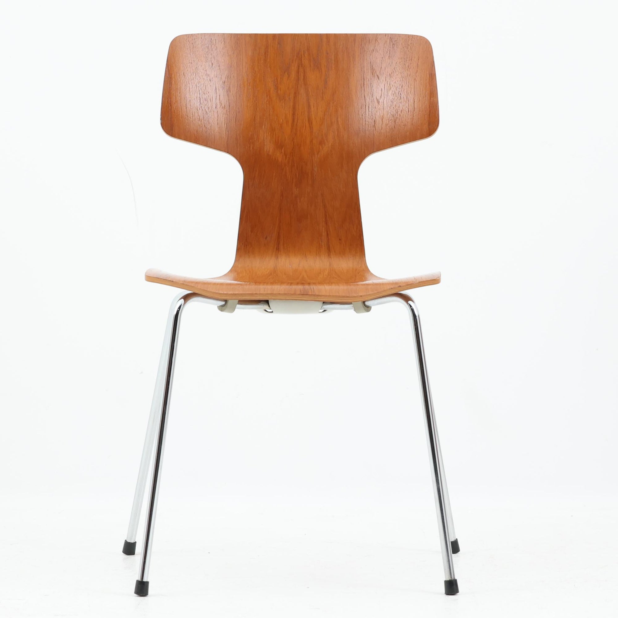 アルネ・ヤコブセンがデザインし、Fritz Hansenが製造した「T Chair」です。チーク材の成形合板による背座一体型のシェルは、背面上部を左右に広げた特徴的なシルエットと、身体に沿う緩やかな曲面が魅力。細身の金属脚との組み合わせが軽快で、ダイニングはもちろん、書斎や玄関のアクセントチェアにもおすすめです。美しい木目と時を重ねた風合い、合理的な構造に宿る北欧ビンテージらしい存在感を楽しめます。