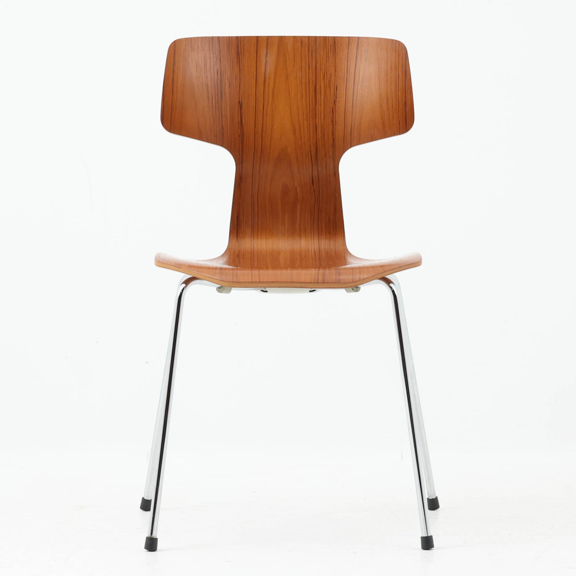アルネ・ヤコブセンがデザインし、Fritz Hansenが製造した「T Chair」です。チーク材の成形合板による背座一体型のシェルは、背面上部を左右に広げた特徴的なシルエットと、身体に沿う緩やかな曲面が魅力。細身の金属脚との組み合わせが軽快で、ダイニングはもちろん、書斎や玄関のアクセントチェアにもおすすめです。美しい木目と時を重ねた風合い、合理的な構造に宿る北欧ビンテージらしい存在感を楽しめます。