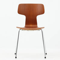 アルネ・ヤコブセンがデザインし、Fritz Hansenが製造した「T Chair」です。チーク材の成形合板による背座一体型のシェルは、背面上部を左右に広げた特徴的なシルエットと、身体に沿う緩やかな曲面が魅力。細身の金属脚との組み合わせが軽快で、ダイニングはもちろん、書斎や玄関のアクセントチェアにもおすすめです。美しい木目と時を重ねた風合い、合理的な構造に宿る北欧ビンテージらしい存在感を楽しめます。