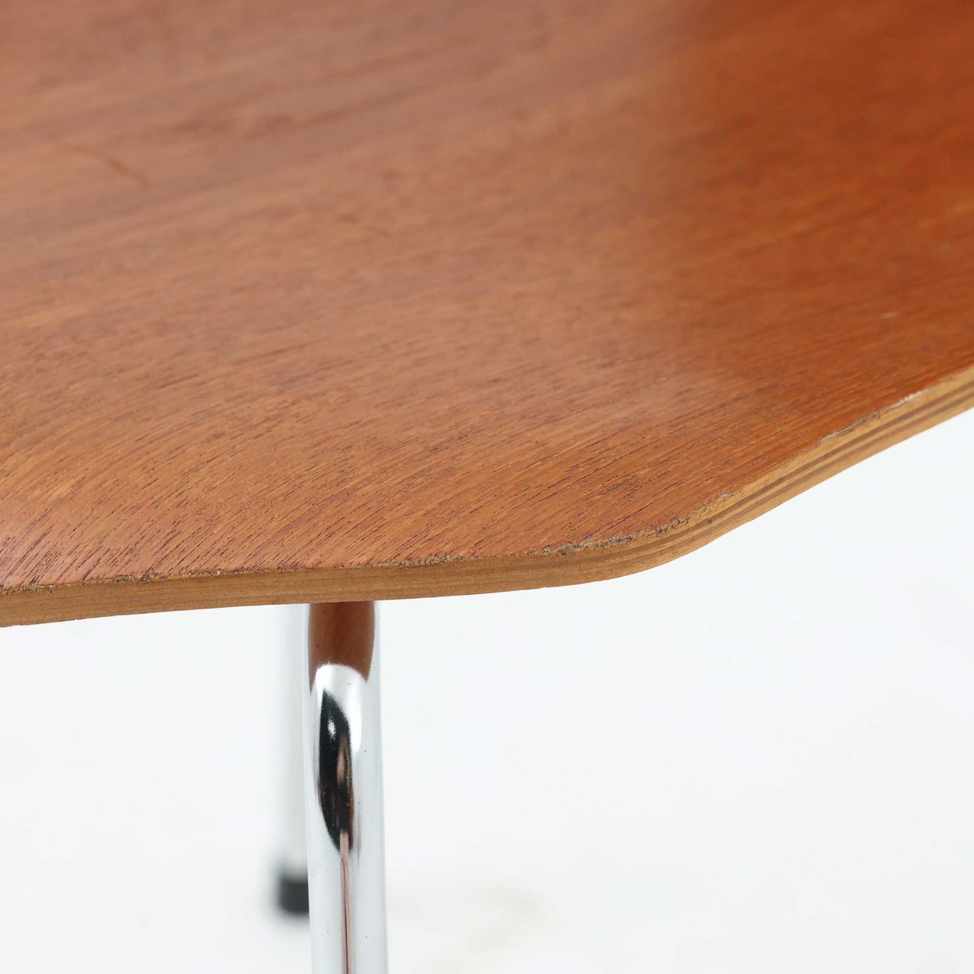 アルネ・ヤコブセンがデザインし、Fritz Hansenが製造した「T Chair」です。チーク材の成形合板による背座一体型のシェルは、背面上部を左右に広げた特徴的なシルエットと、身体に沿う緩やかな曲面が魅力。細身の金属脚との組み合わせが軽快で、ダイニングはもちろん、書斎や玄関のアクセントチェアにもおすすめです。美しい木目と時を重ねた風合い、合理的な構造に宿る北欧ビンテージらしい存在感を楽しめます。
