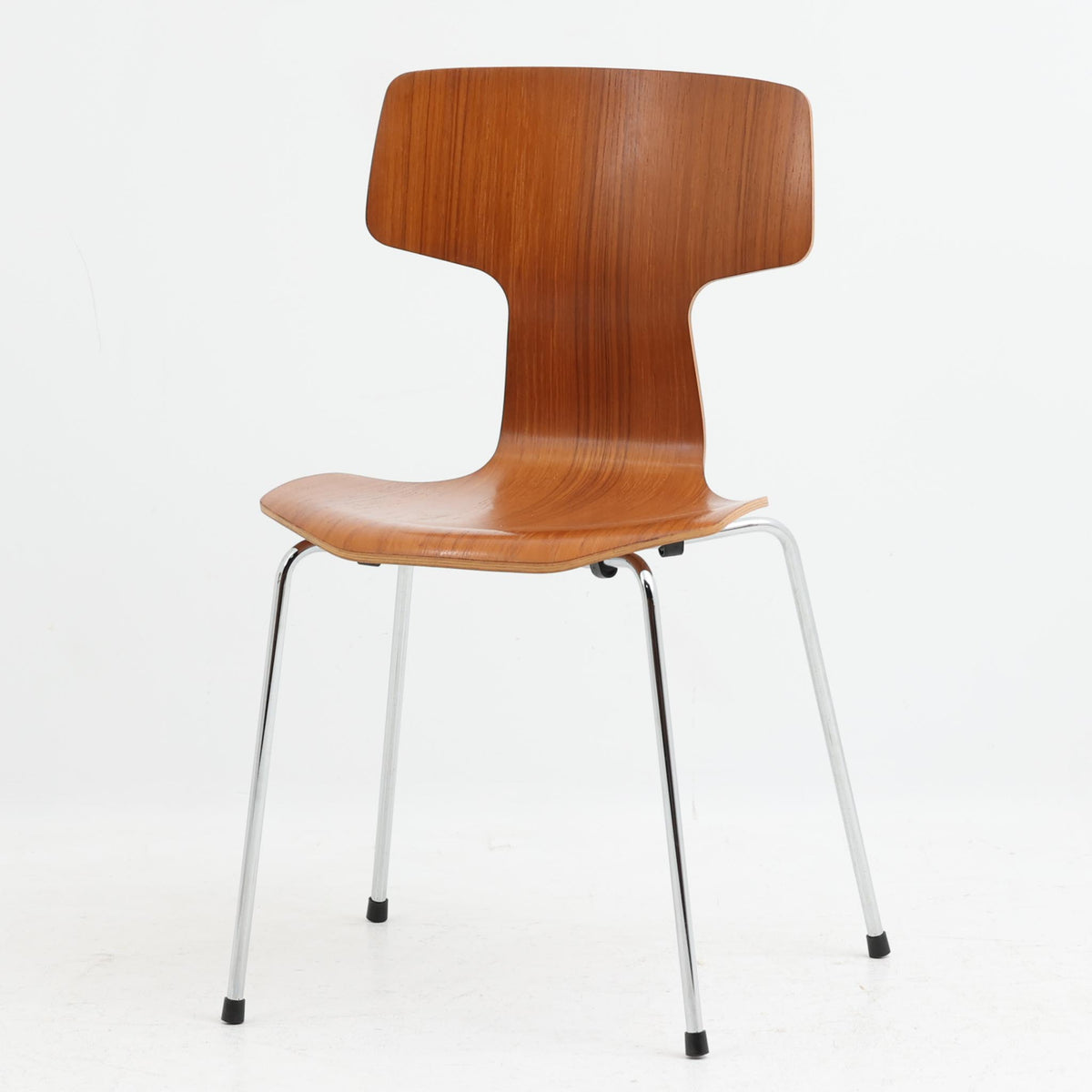 アルネ・ヤコブセンがデザインし、Fritz Hansenが製造した「T Chair」です。チーク材の成形合板による背座一体型のシェルは、背面上部を左右に広げた特徴的なシルエットと、身体に沿う緩やかな曲面が魅力。細身の金属脚との組み合わせが軽快で、ダイニングはもちろん、書斎や玄関のアクセントチェアにもおすすめです。美しい木目と時を重ねた風合い、合理的な構造に宿る北欧ビンテージらしい存在感を楽しめます。