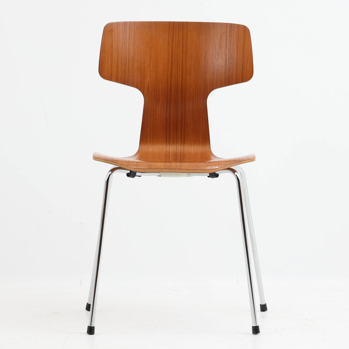 アルネ・ヤコブセンがデザインし、Fritz Hansenが製造した「T Chair」です。チーク材の成形合板による背座一体型のシェルは、背面上部を左右に広げた特徴的なシルエットと、身体に沿う緩やかな曲面が魅力。細身の金属脚との組み合わせが軽快で、ダイニングはもちろん、書斎や玄関のアクセントチェアにもおすすめです。美しい木目と時を重ねた風合い、合理的な構造に宿る北欧ビンテージらしい存在感を楽しめます。
