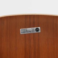 アルネ・ヤコブセンがデザインし、Fritz Hansenが製造した「T Chair」です。チーク材の成形合板による背座一体型のシェルは、背面上部を左右に広げた特徴的なシルエットと、身体に沿う緩やかな曲面が魅力。細身の金属脚との組み合わせが軽快で、ダイニングはもちろん、書斎や玄関のアクセントチェアにもおすすめです。美しい木目と時を重ねた風合い、合理的な構造に宿る北欧ビンテージらしい存在感を楽しめます。
