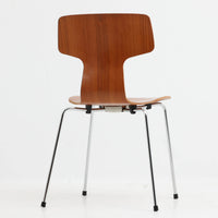 アルネ・ヤコブセンがデザインし、Fritz Hansenが製造した「T Chair」です。チーク材の成形合板による背座一体型のシェルは、背面上部を左右に広げた特徴的なシルエットと、身体に沿う緩やかな曲面が魅力。細身の金属脚との組み合わせが軽快で、ダイニングはもちろん、書斎や玄関のアクセントチェアにもおすすめです。美しい木目と時を重ねた風合い、合理的な構造に宿る北欧ビンテージらしい存在感を楽しめます。