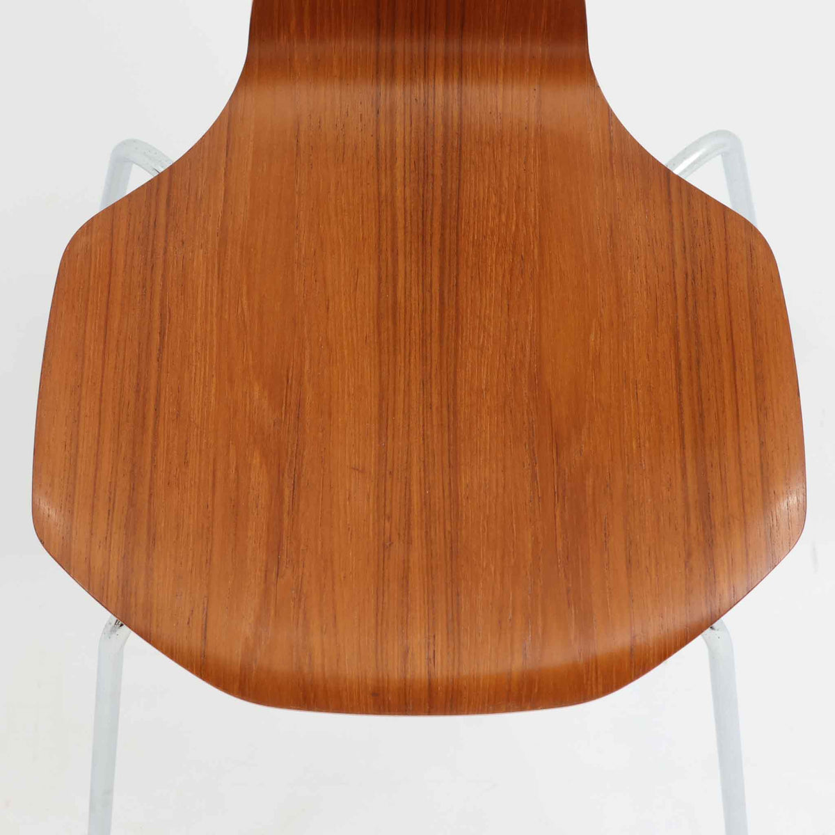 アルネ・ヤコブセンがデザインし、Fritz Hansenが製造した「T Chair」です。チーク材の成形合板による背座一体型のシェルは、背面上部を左右に広げた特徴的なシルエットと、身体に沿う緩やかな曲面が魅力。細身の金属脚との組み合わせが軽快で、ダイニングはもちろん、書斎や玄関のアクセントチェアにもおすすめです。美しい木目と時を重ねた風合い、合理的な構造に宿る北欧ビンテージらしい存在感を楽しめます。