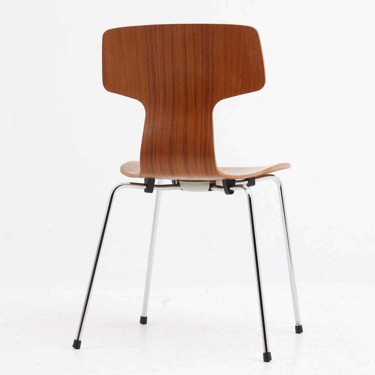 アルネ・ヤコブセンがデザインし、Fritz Hansenが製造した「T Chair」です。チーク材の成形合板による背座一体型のシェルは、背面上部を左右に広げた特徴的なシルエットと、身体に沿う緩やかな曲面が魅力。細身の金属脚との組み合わせが軽快で、ダイニングはもちろん、書斎や玄関のアクセントチェアにもおすすめです。美しい木目と時を重ねた風合い、合理的な構造に宿る北欧ビンテージらしい存在感を楽しめます。