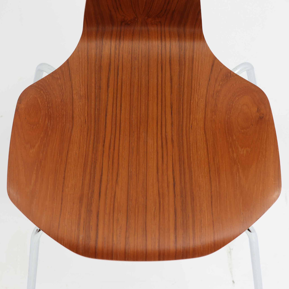 アルネ・ヤコブセンがデザインし、Fritz Hansenが製造した「T Chair」です。チーク材の成形合板による背座一体型のシェルは、背面上部を左右に広げた特徴的なシルエットと、身体に沿う緩やかな曲面が魅力。細身の金属脚との組み合わせが軽快で、ダイニングはもちろん、書斎や玄関のアクセントチェアにもおすすめです。美しい木目と時を重ねた風合い、合理的な構造に宿る北欧ビンテージらしい存在感を楽しめます。
