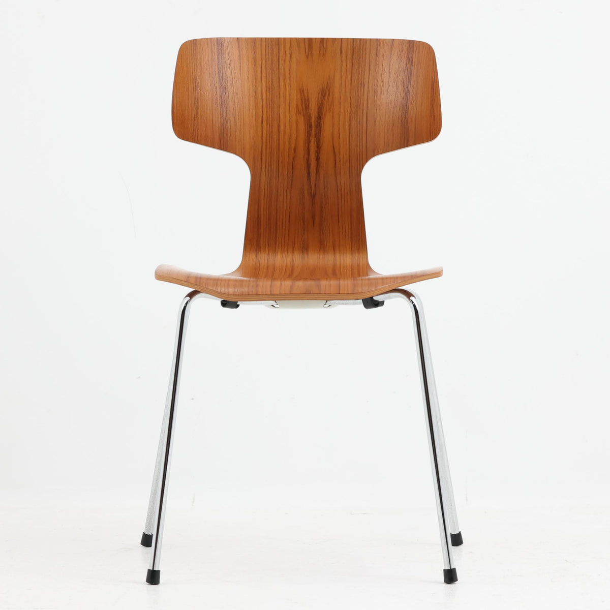 アルネ・ヤコブセンがデザインし、Fritz Hansenが製造した「T Chair」です。チーク材の成形合板による背座一体型のシェルは、背面上部を左右に広げた特徴的なシルエットと、身体に沿う緩やかな曲面が魅力。細身の金属脚との組み合わせが軽快で、ダイニングはもちろん、書斎や玄関のアクセントチェアにもおすすめです。美しい木目と時を重ねた風合い、合理的な構造に宿る北欧ビンテージらしい存在感を楽しめます。