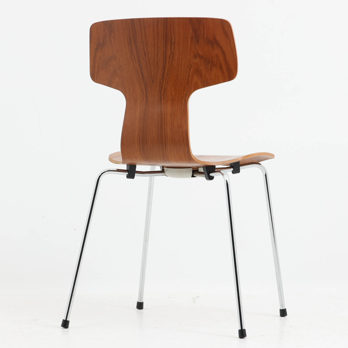 アルネ・ヤコブセンがデザインし、Fritz Hansenが製造した「T Chair」です。チーク材の成形合板による背座一体型のシェルは、背面上部を左右に広げた特徴的なシルエットと、身体に沿う緩やかな曲面が魅力。細身の金属脚との組み合わせが軽快で、ダイニングはもちろん、書斎や玄関のアクセントチェアにもおすすめです。美しい木目と時を重ねた風合い、合理的な構造に宿る北欧ビンテージらしい存在感を楽しめます。