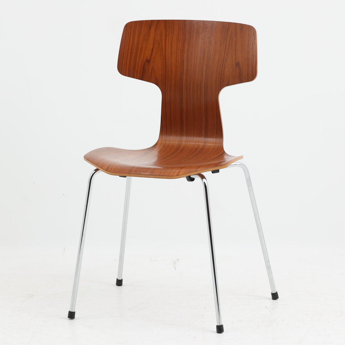 アルネ・ヤコブセンがデザインし、Fritz Hansenが製造した「T Chair」です。チーク材の成形合板による背座一体型のシェルは、背面上部を左右に広げた特徴的なシルエットと、身体に沿う緩やかな曲面が魅力。細身の金属脚との組み合わせが軽快で、ダイニングはもちろん、書斎や玄関のアクセントチェアにもおすすめです。美しい木目と時を重ねた風合い、合理的な構造に宿る北欧ビンテージらしい存在感を楽しめます。