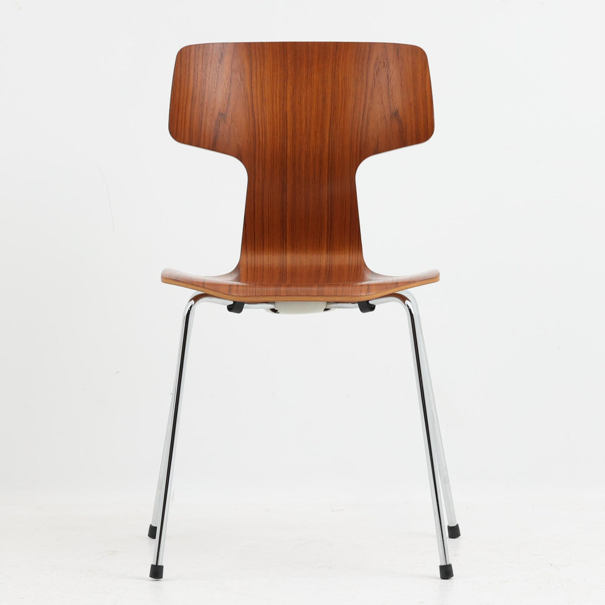 アルネ・ヤコブセンがデザインし、Fritz Hansenが製造した「T Chair」です。チーク材の成形合板による背座一体型のシェルは、背面上部を左右に広げた特徴的なシルエットと、身体に沿う緩やかな曲面が魅力。細身の金属脚との組み合わせが軽快で、ダイニングはもちろん、書斎や玄関のアクセントチェアにもおすすめです。美しい木目と時を重ねた風合い、合理的な構造に宿る北欧ビンテージらしい存在感を楽しめます。