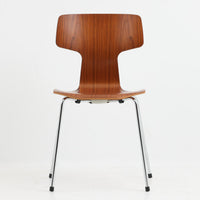 アルネ・ヤコブセンがデザインし、Fritz Hansenが製造した「T Chair」です。チーク材の成形合板による背座一体型のシェルは、背面上部を左右に広げた特徴的なシルエットと、身体に沿う緩やかな曲面が魅力。細身の金属脚との組み合わせが軽快で、ダイニングはもちろん、書斎や玄関のアクセントチェアにもおすすめです。美しい木目と時を重ねた風合い、合理的な構造に宿る北欧ビンテージらしい存在感を楽しめます。