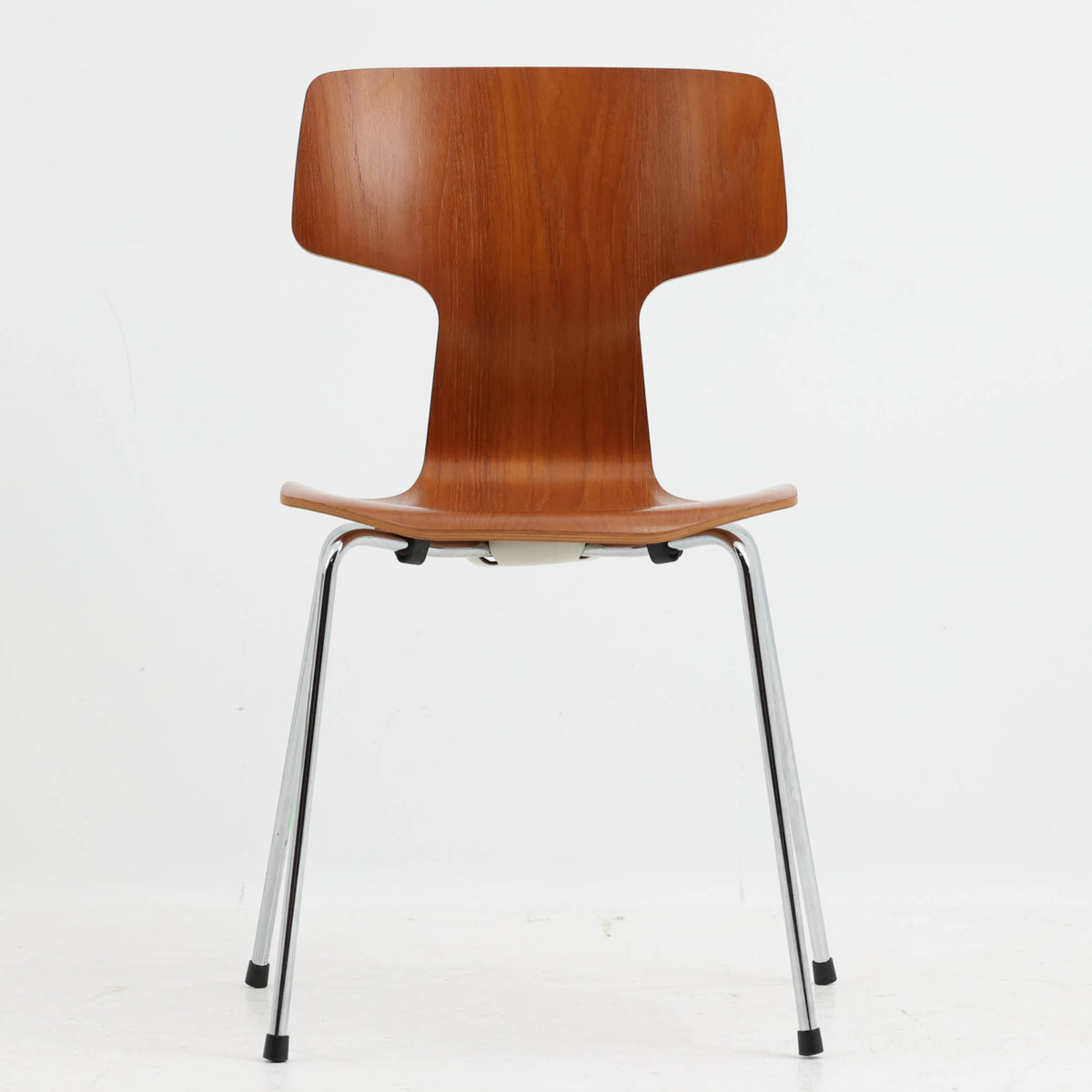 アルネ・ヤコブセンがデザインし、Fritz Hansenが製造した「T Chair」です。チーク材の成形合板による背座一体型のシェルは、背面上部を左右に広げた特徴的なシルエットと、身体に沿う緩やかな曲面が魅力。細身の金属脚との組み合わせが軽快で、ダイニングはもちろん、書斎や玄関のアクセントチェアにもおすすめです。美しい木目と時を重ねた風合い、合理的な構造に宿る北欧ビンテージらしい存在感を楽しめます。