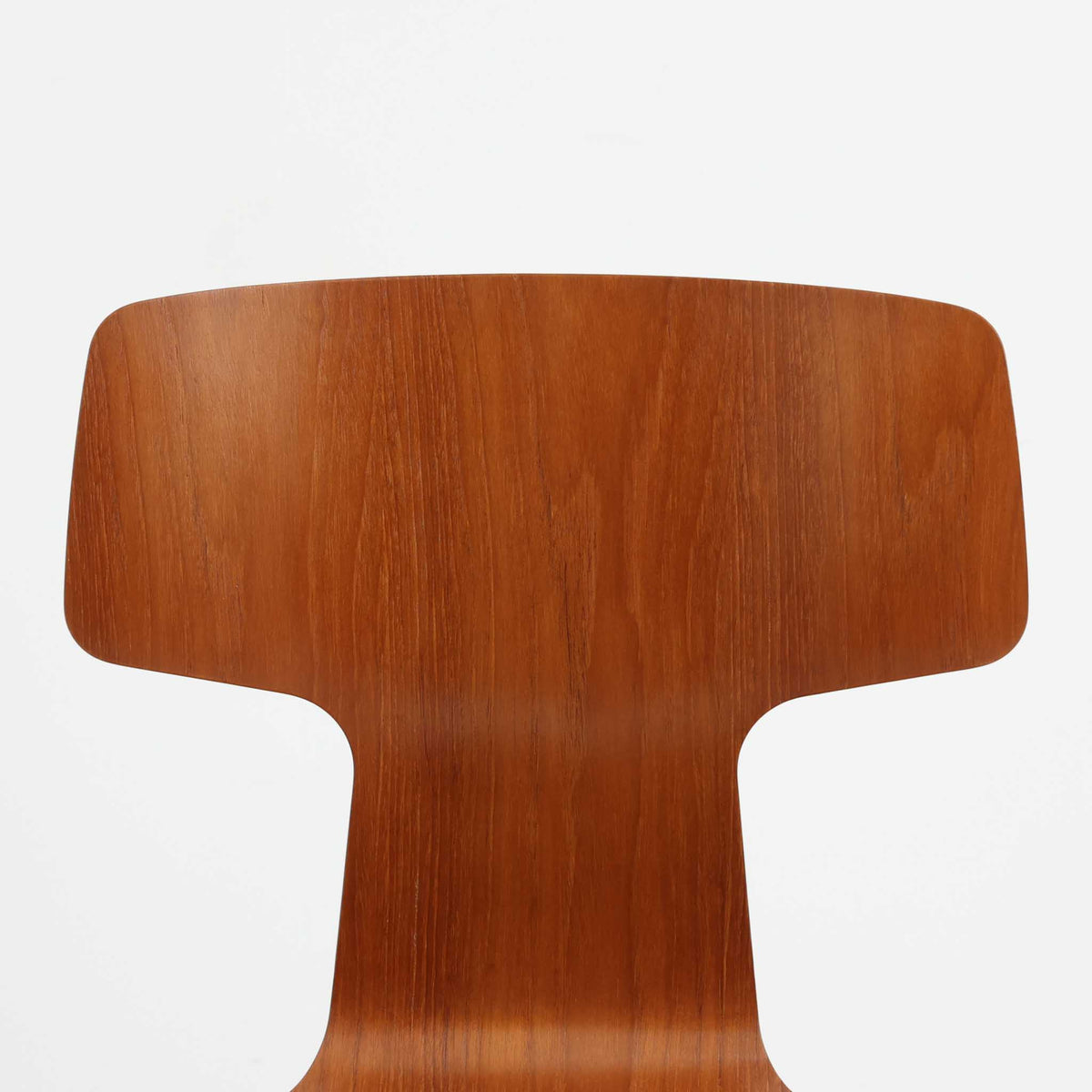 アルネ・ヤコブセンがデザインし、Fritz Hansenが製造した「T Chair」です。チーク材の成形合板による背座一体型のシェルは、背面上部を左右に広げた特徴的なシルエットと、身体に沿う緩やかな曲面が魅力。細身の金属脚との組み合わせが軽快で、ダイニングはもちろん、書斎や玄関のアクセントチェアにもおすすめです。美しい木目と時を重ねた風合い、合理的な構造に宿る北欧ビンテージらしい存在感を楽しめます。