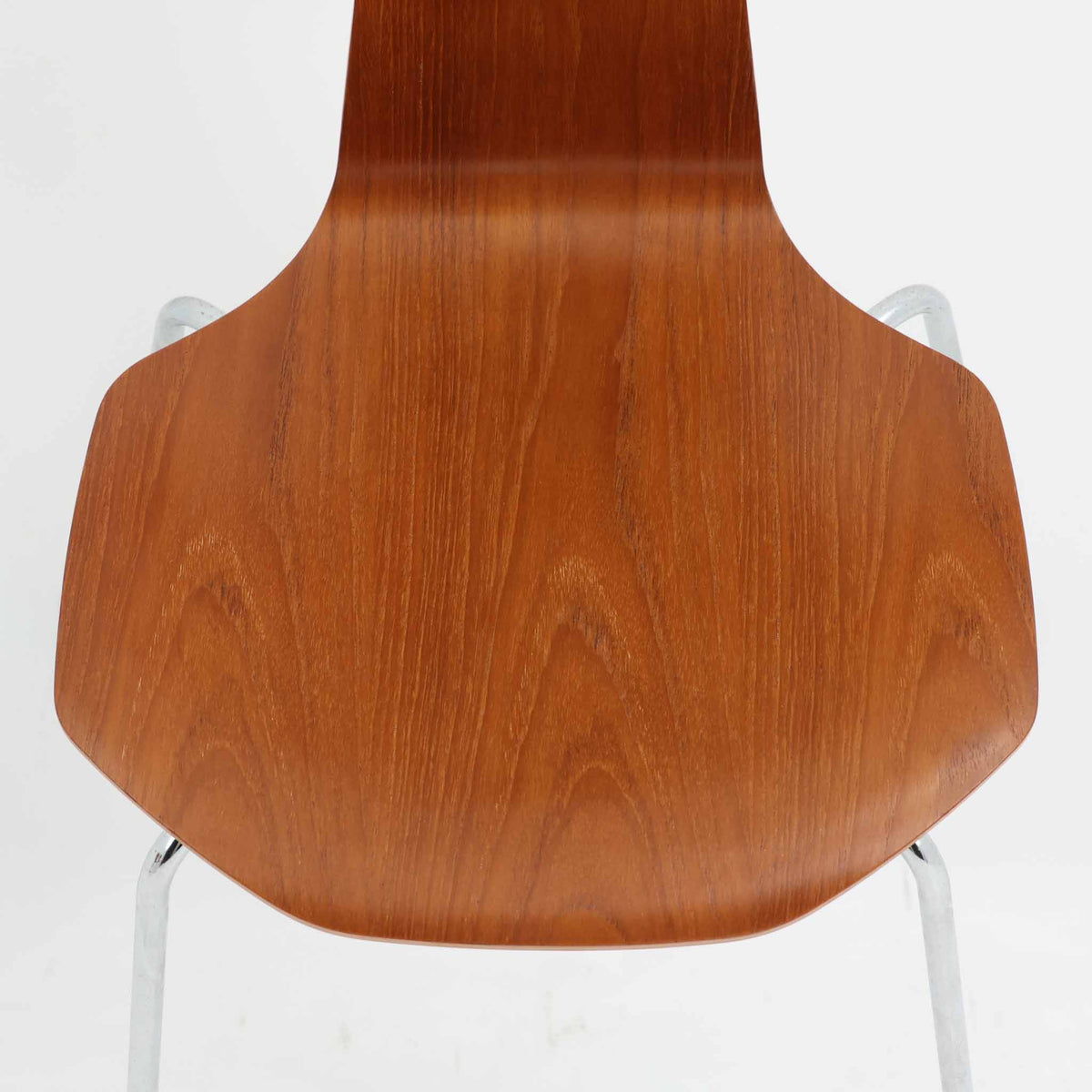 アルネ・ヤコブセンがデザインし、Fritz Hansenが製造した「T Chair」です。チーク材の成形合板による背座一体型のシェルは、背面上部を左右に広げた特徴的なシルエットと、身体に沿う緩やかな曲面が魅力。細身の金属脚との組み合わせが軽快で、ダイニングはもちろん、書斎や玄関のアクセントチェアにもおすすめです。美しい木目と時を重ねた風合い、合理的な構造に宿る北欧ビンテージらしい存在感を楽しめます。