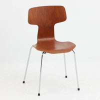 アルネ・ヤコブセンがデザインし、Fritz Hansenが製造した「T Chair」です。チーク材の成形合板による背座一体型のシェルは、背面上部を左右に広げた特徴的なシルエットと、身体に沿う緩やかな曲面が魅力。細身の金属脚との組み合わせが軽快で、ダイニングはもちろん、書斎や玄関のアクセントチェアにもおすすめです。美しい木目と時を重ねた風合い、合理的な構造に宿る北欧ビンテージらしい存在感を楽しめます。