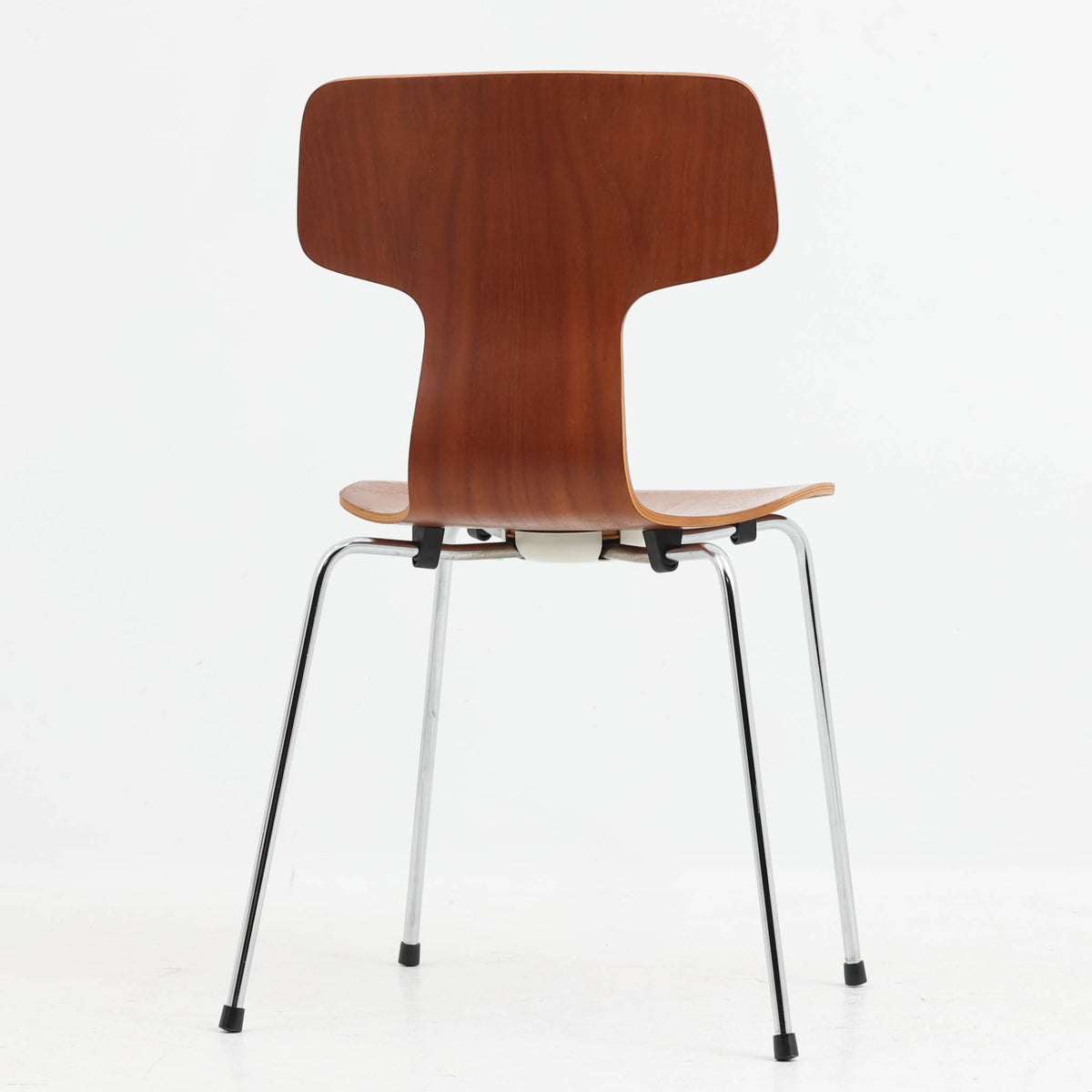 アルネ・ヤコブセンがデザインし、Fritz Hansenが製造した「T Chair」です。チーク材の成形合板による背座一体型のシェルは、背面上部を左右に広げた特徴的なシルエットと、身体に沿う緩やかな曲面が魅力。細身の金属脚との組み合わせが軽快で、ダイニングはもちろん、書斎や玄関のアクセントチェアにもおすすめです。美しい木目と時を重ねた風合い、合理的な構造に宿る北欧ビンテージらしい存在感を楽しめます。