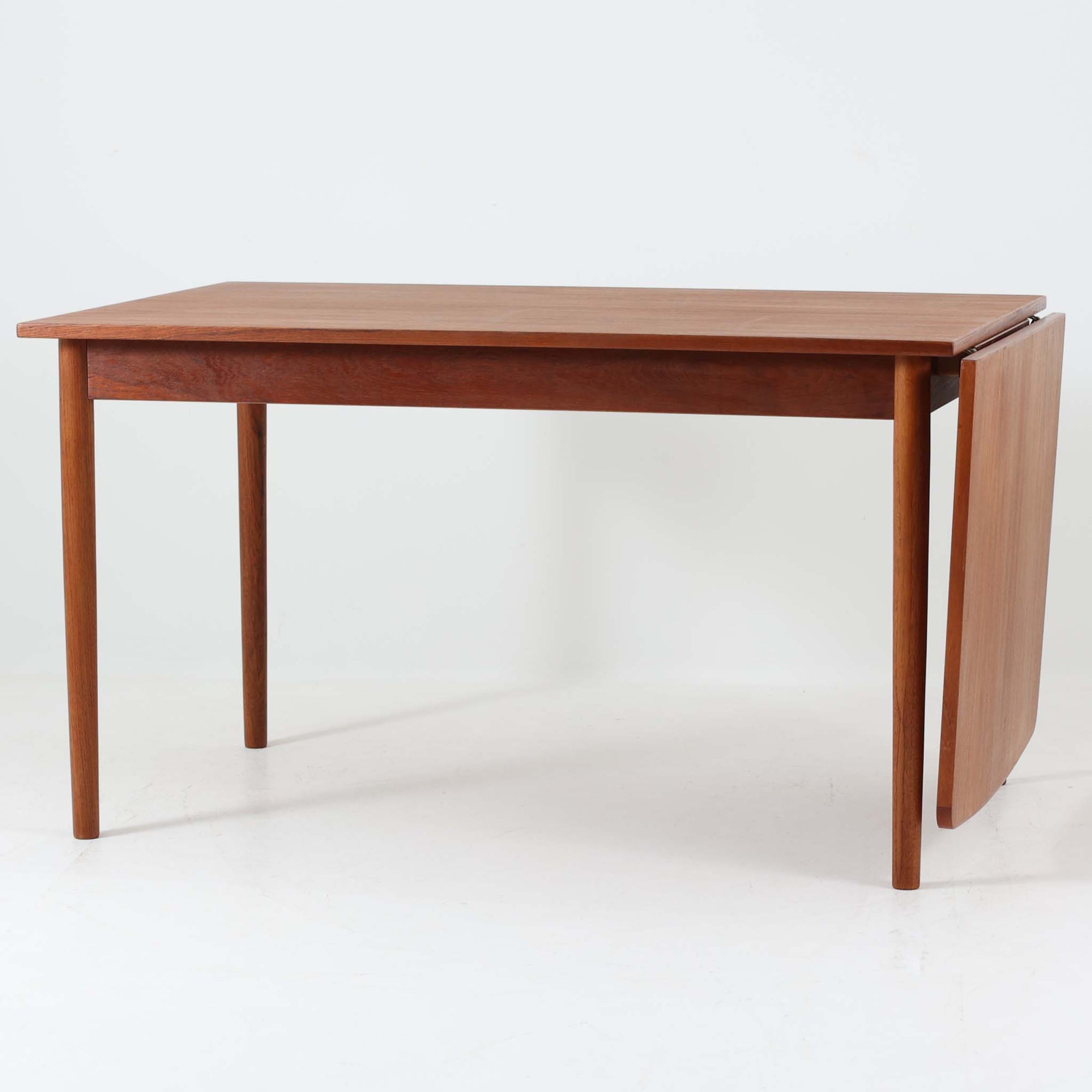 デンマークのHundevad & Co社によるバタフライ式のダイニングテーブルは、希少なチーク材を使用した上品な佇まいと、幅133cmから195cmへと片側の拡張板でサイズ調整が可能な機能性が魅力の一台です。普段はコンパクトに、必要に応じて天板を広げて使える設計は、日常から来客時まで幅広く活躍します。直線的なフレームと繊細な脚部が調和し、空間に北欧ビンテージらしい落ち着きと温かみを添えてくれます。