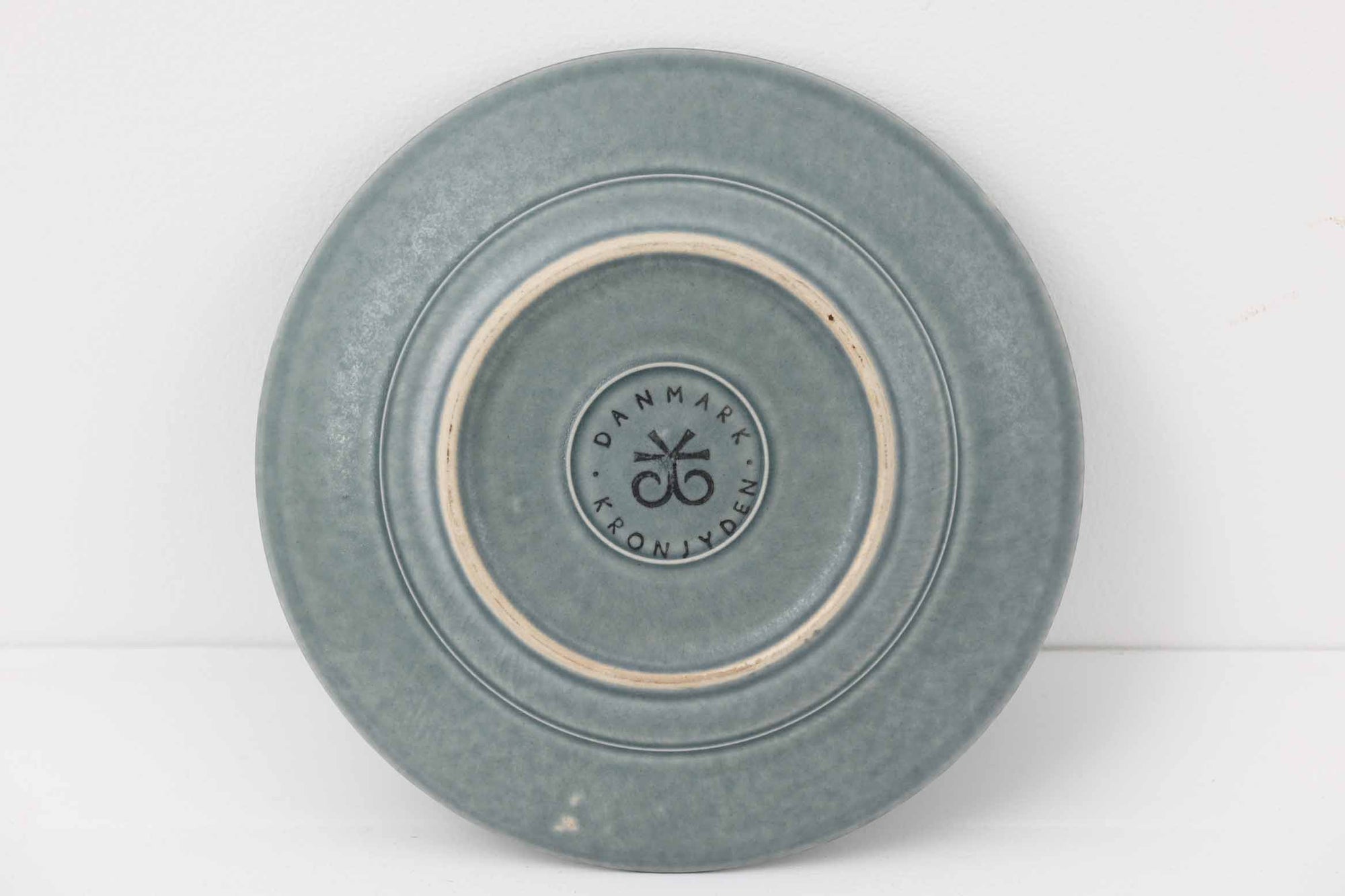 Kronjydenアズール、ブルーカラーのプレートです。1957年にKronjydenから制作が始まったシリーズは、その後Nissen、Bing&amp;Grondahlと引き継がれ長く愛されたシリーズとなりました。デンマークではスウェーデンやフィンランドの陶器メーカーと並んで今でも非常に人気のある商品となります。