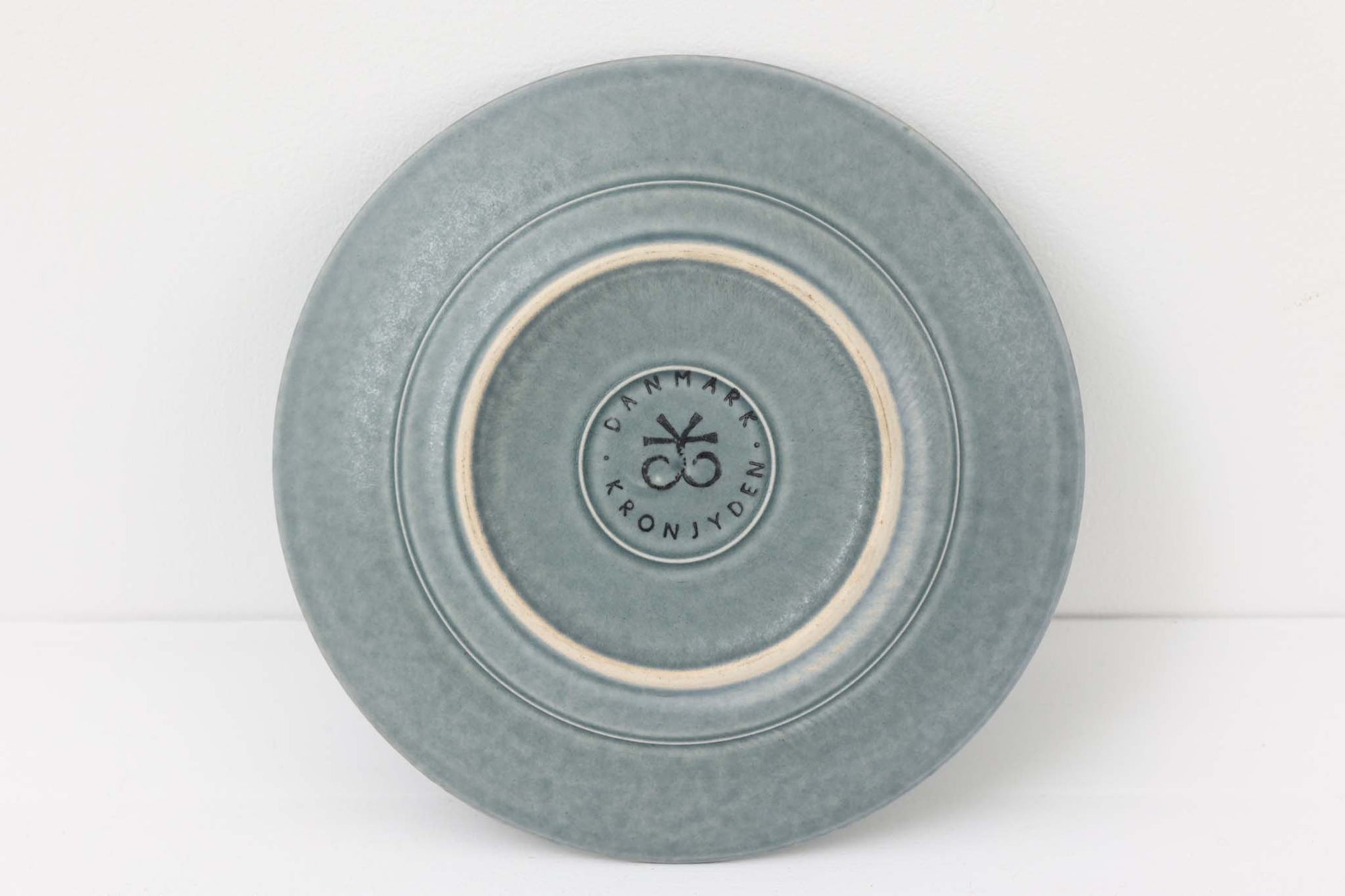 Kronjydenアズール、ブルーカラーのプレートです。1957年にKronjydenから制作が始まったシリーズは、その後Nissen、Bing&amp;Grondahlと引き継がれ長く愛されたシリーズとなりました。デンマークではスウェーデンやフィンランドの陶器メーカーと並んで今でも非常に人気のある商品となります。