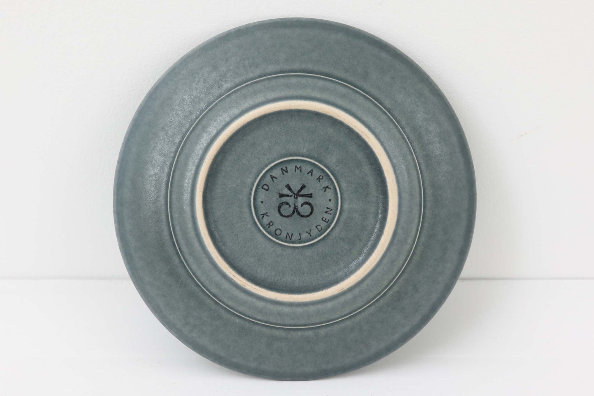 Kronjydenアズール、ブルーカラーのプレートです。1957年にKronjydenから制作が始まったシリーズは、その後Nissen、Bing&amp;Grondahlと引き継がれ長く愛されたシリーズとなりました。デンマークではスウェーデンやフィンランドの陶器メーカーと並んで今でも非常に人気のある商品となります。
