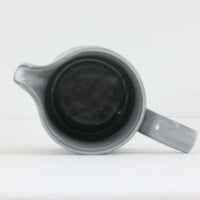 デンマークを代表するデザイナー、イェンス・H・クイストゴーによる「Cordial（コーディアル）」シリーズのヴィンテージ・ミルクジャグ（ピッチャー）です。1960年代にKronjydenから制作が始まったシリーズは、その後Nissen、Bing&Grondahlと引き継がれ長く愛されたシリーズとなりました。淡いグレーのストーンウェアにハートを連想させる繊細な型押し模様が施されており、デンマークではスウェーデンやフィンランドの陶器メーカーと並んで今でも非常に人気のある商品となります。