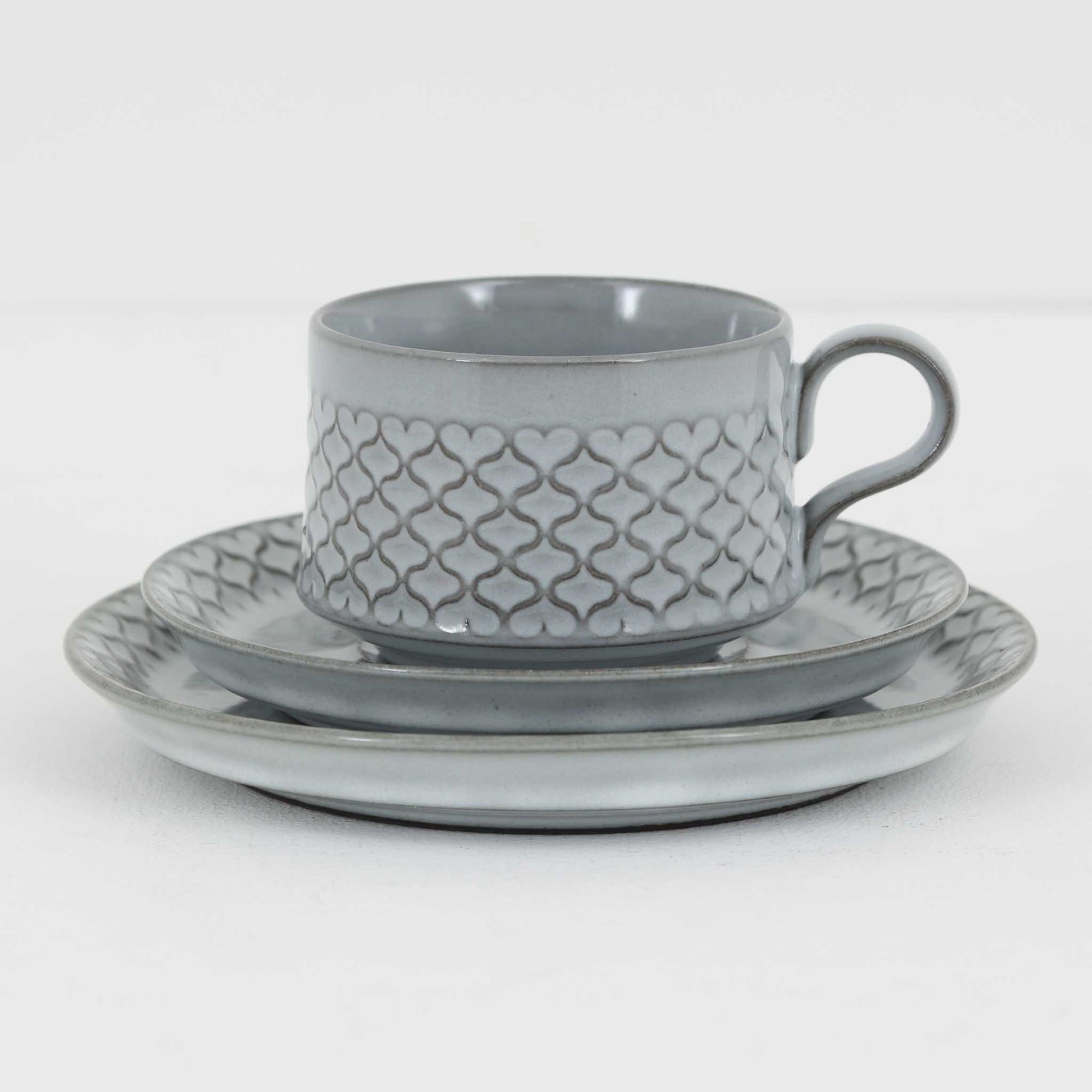 デンマークを代表するデザイナー、イェンス・H・クイストゴーによる「Cordial（コーディアル）」シリーズのヴィンテージ・トリオセット（ティーカップ、ソーサー、プレート）です。1960年代にKronjydenから制作が始まったシリーズは、その後Nissen、Bing&Grondahlと引き継がれ長く愛されたシリーズとなりました。淡いグレーのストーンウェアにハートを連想させる繊細な型押し模様が施されており、デンマークではスウェーデンやフィンランドの陶器メーカーと並んで今でも非常に人気のある商品となります。
